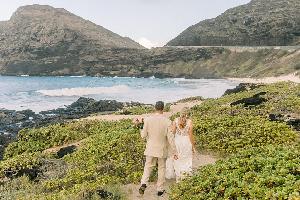 Newlyweds walk down a beach trail on Oahu 