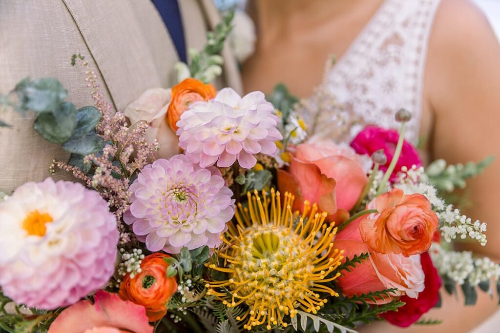 Details of a bride's colorful bouquet while she and her husband hold them