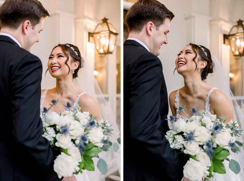 A bride laughs with her groom on a porch while holding her bouquet 
