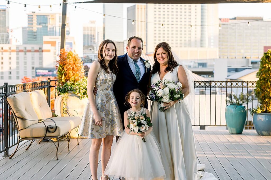 Newlyweds stand with their two daughters on a balcony at their Terminus 330 Wedding in Atlanta, Georgia