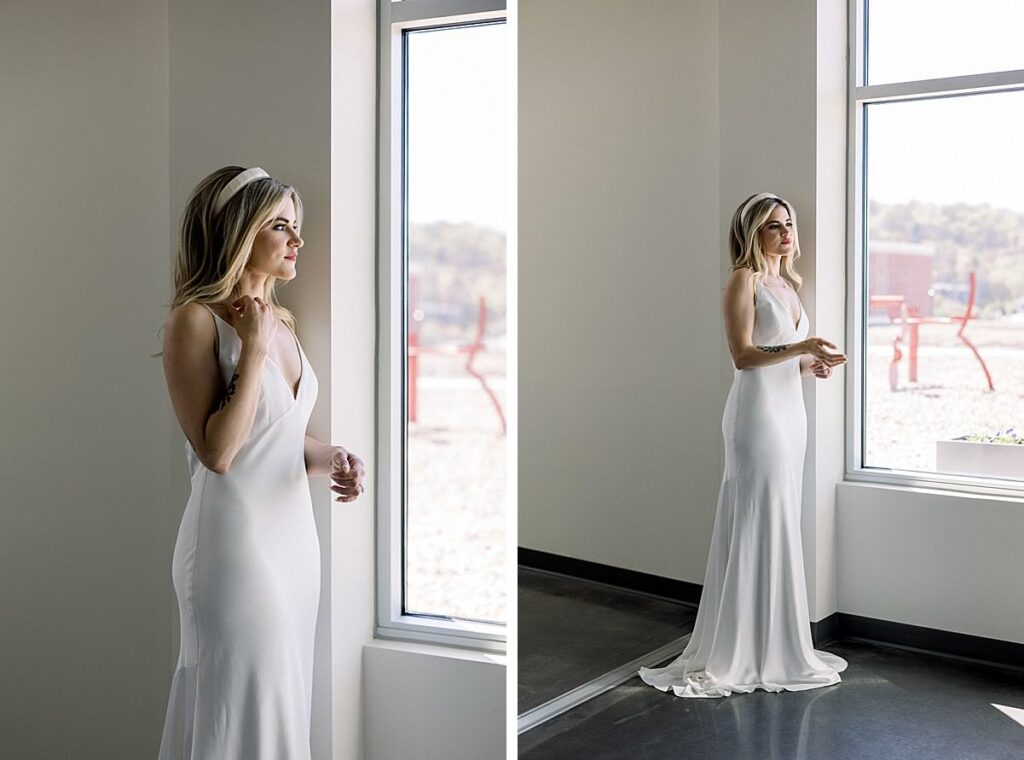 A bride gets ready and looks out the window in her white silk dress