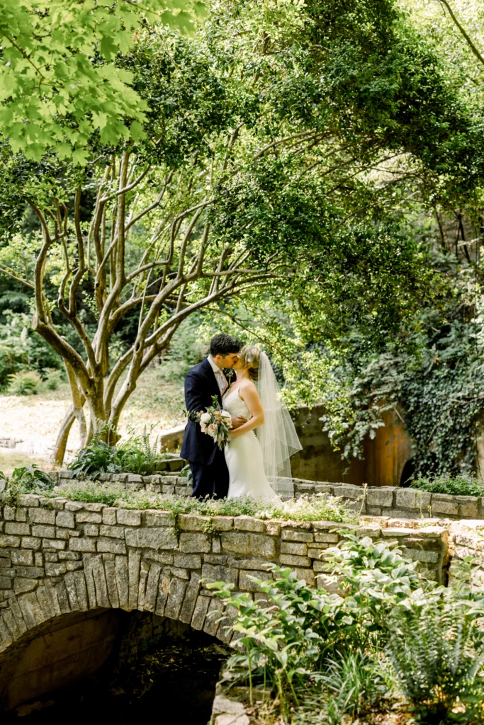 bride and groom sharing a kiss near the stone wall at the Cator Woolford Gardens Wedding Venue