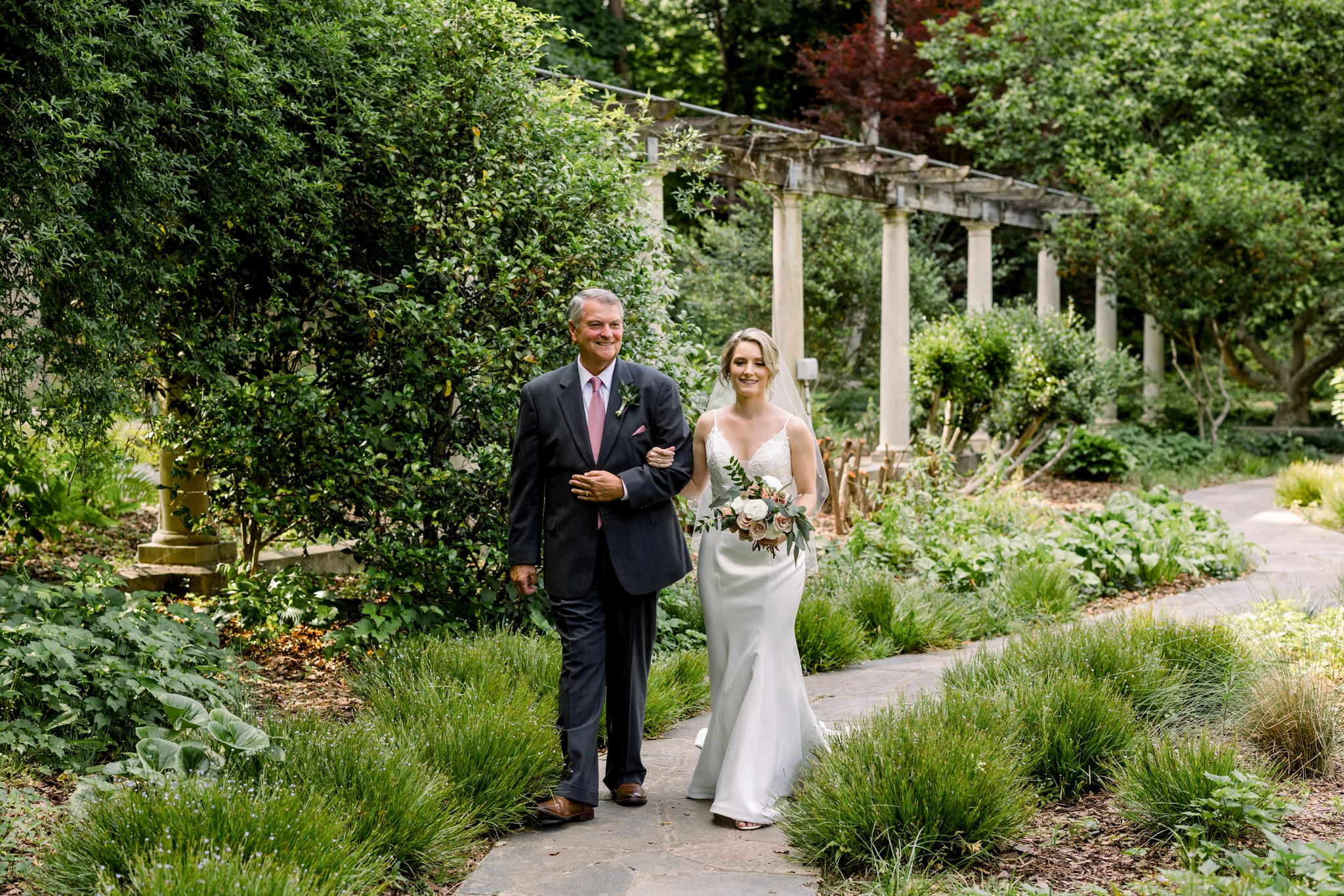 bride and her dad walking down the aisle in a garden