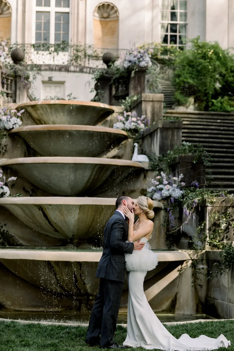 bride and groom sharing a kiss in front of the Swan House fountain