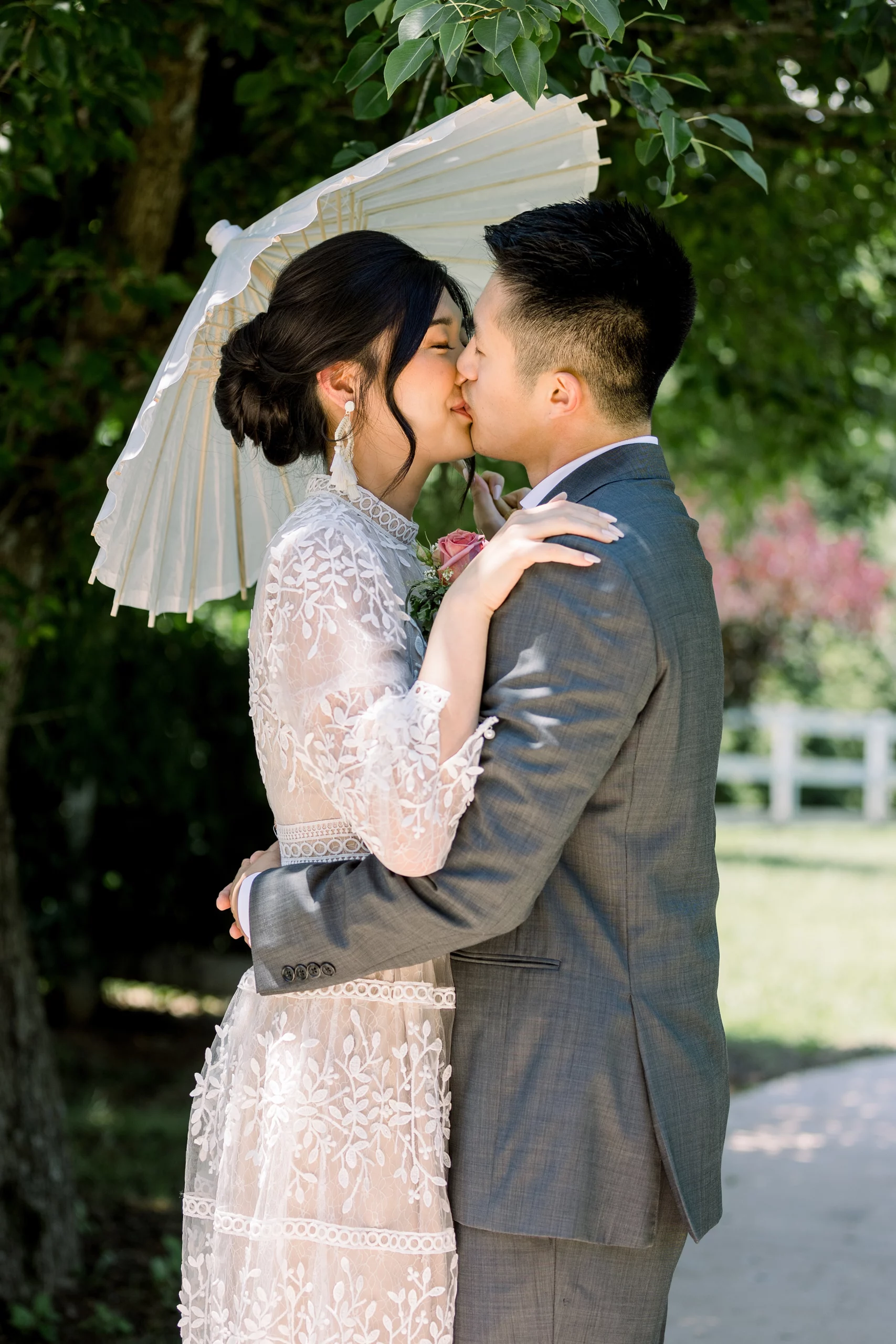 bride and groom sharing a kiss under a parisol The Wildflower Barn wedding