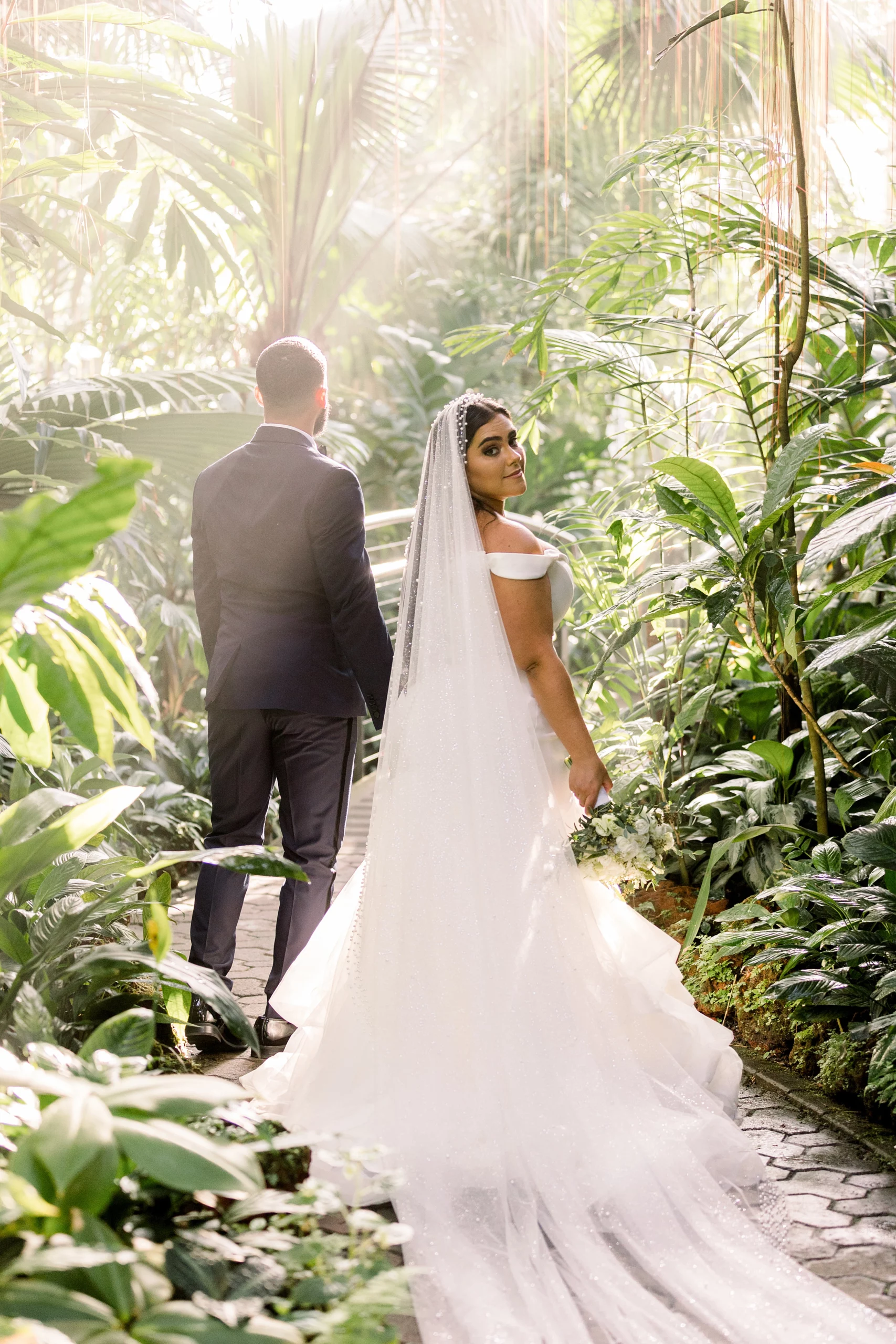 bride and groom standing in a garden with sunlight shining through at an Atlanta botanical gardens wedding