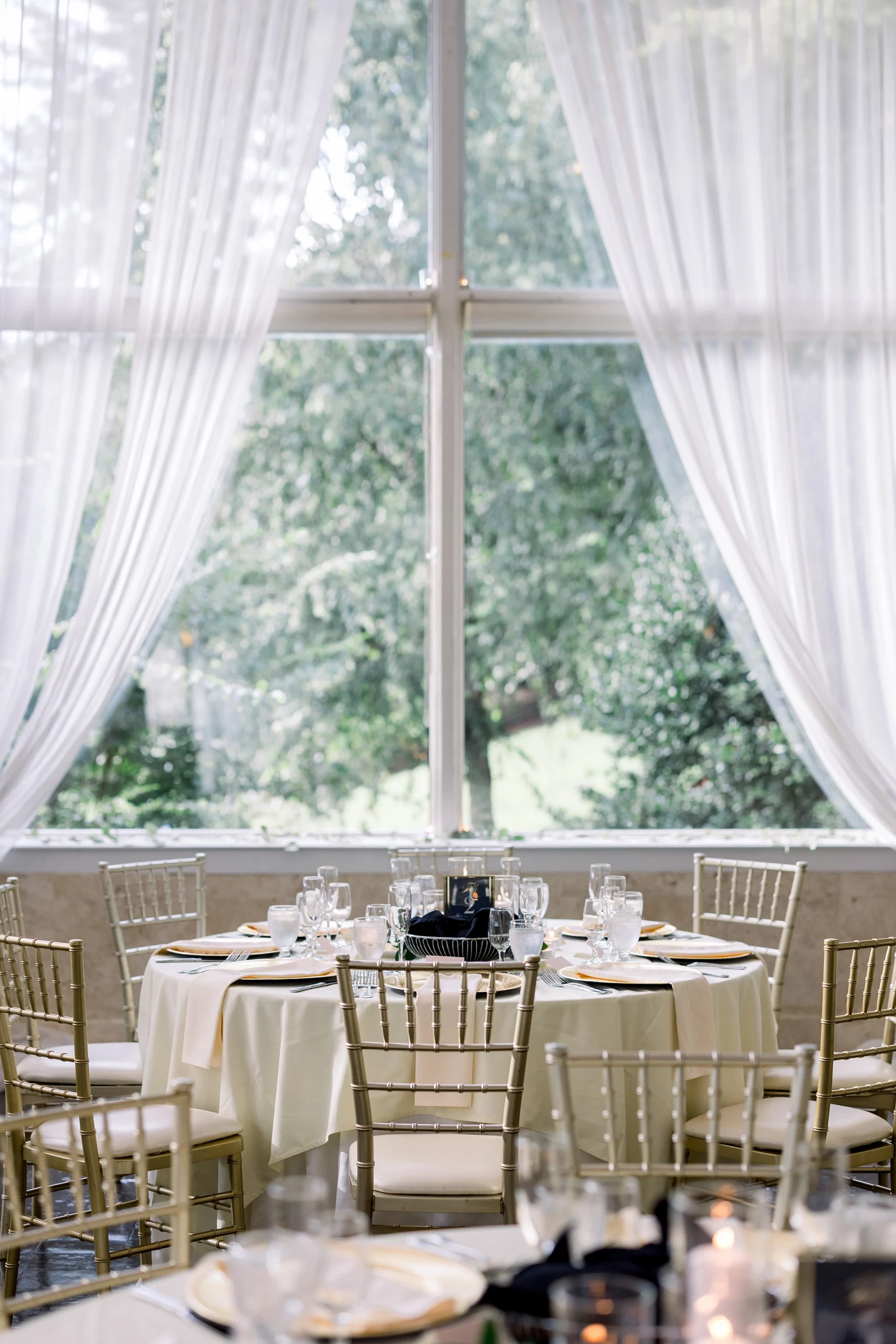 A table setting under a window for a wedding reception