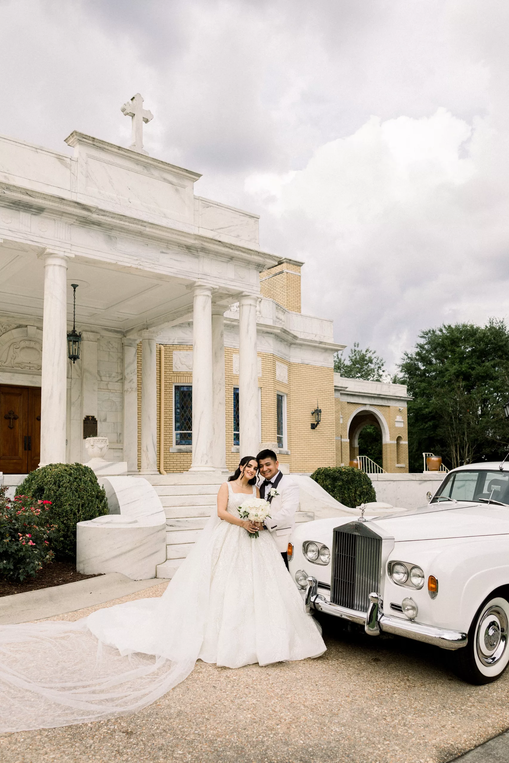 Newlyweds lean against an antique limo in front of the Biltmore Ballrooms Wedding venue