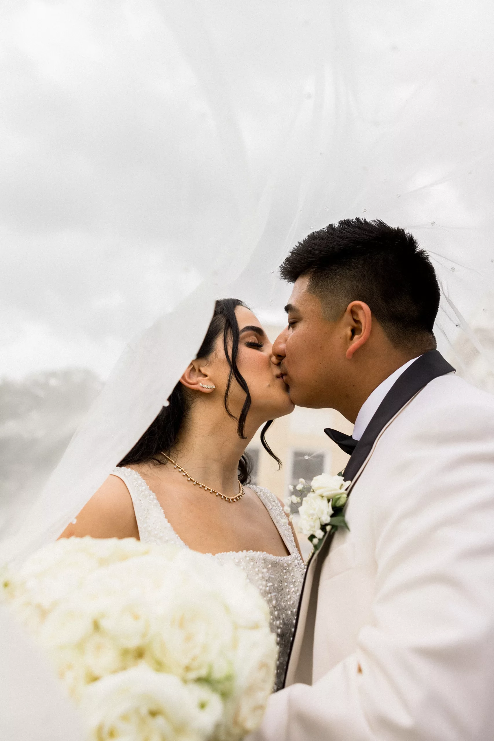 Newlyweds kiss while hiding under the long veil