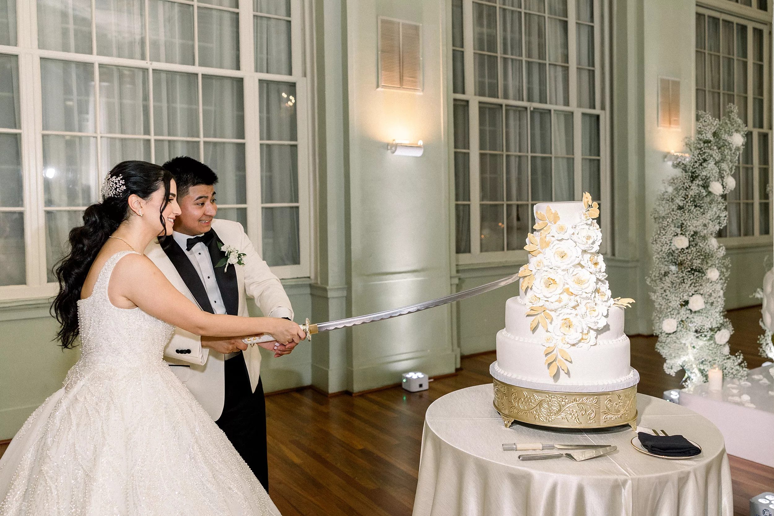 Newlyweds cut their four tier cake with a long katana sword at their Biltmore Ballrooms Wedding