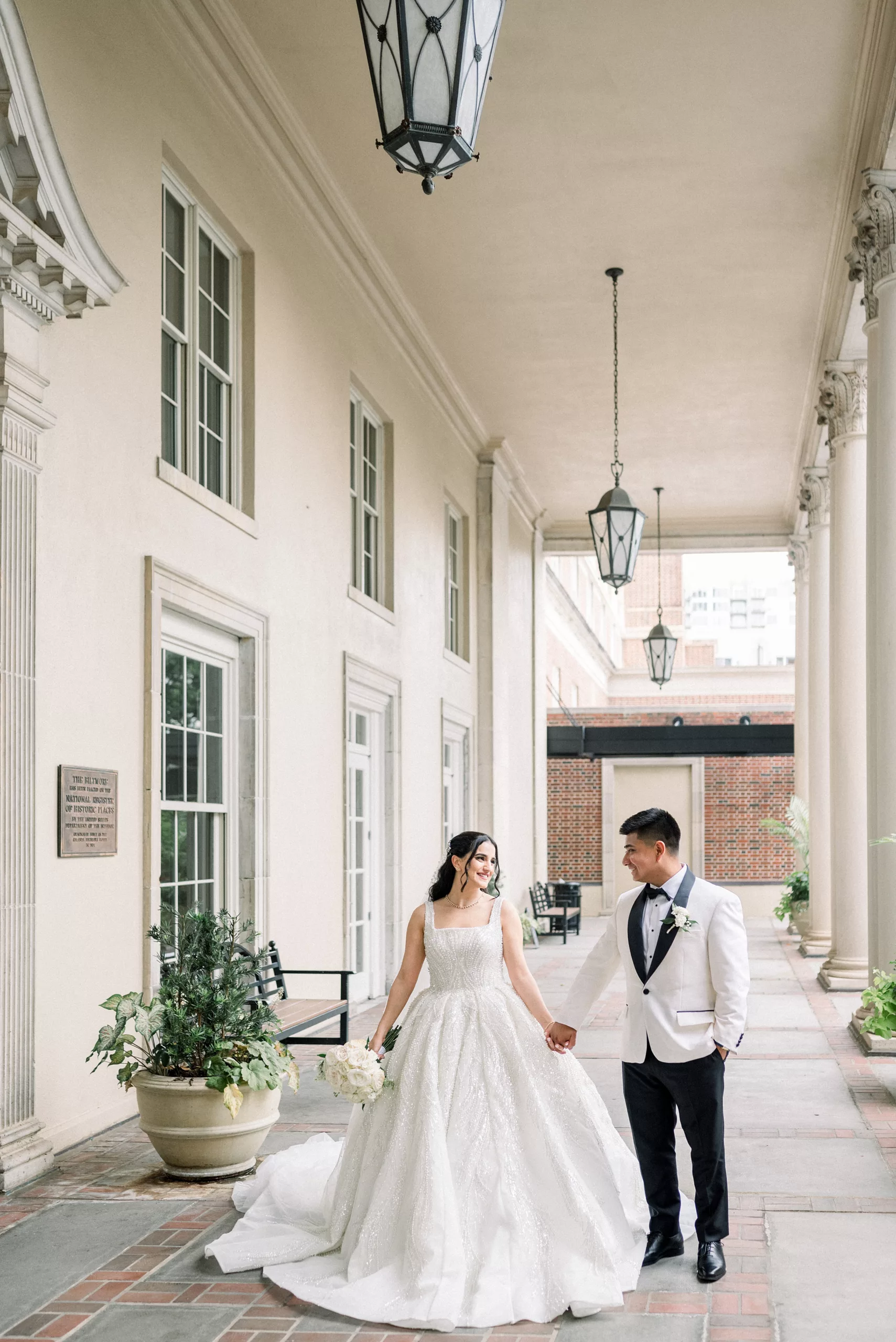 Newlyweds walk down the front porch holding hands at the Biltmore Ballrooms Wedding venue