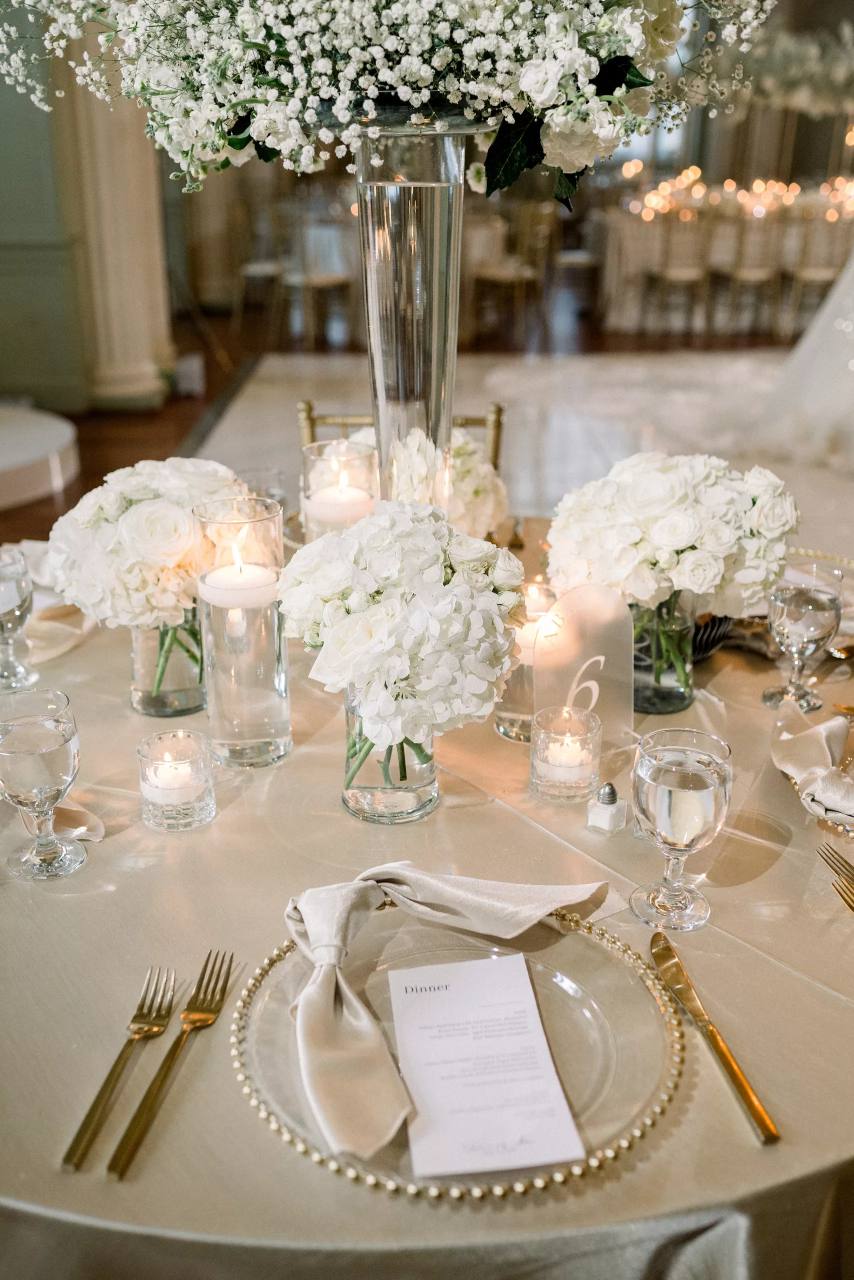 Details of a reception table with white roses and gold utensils