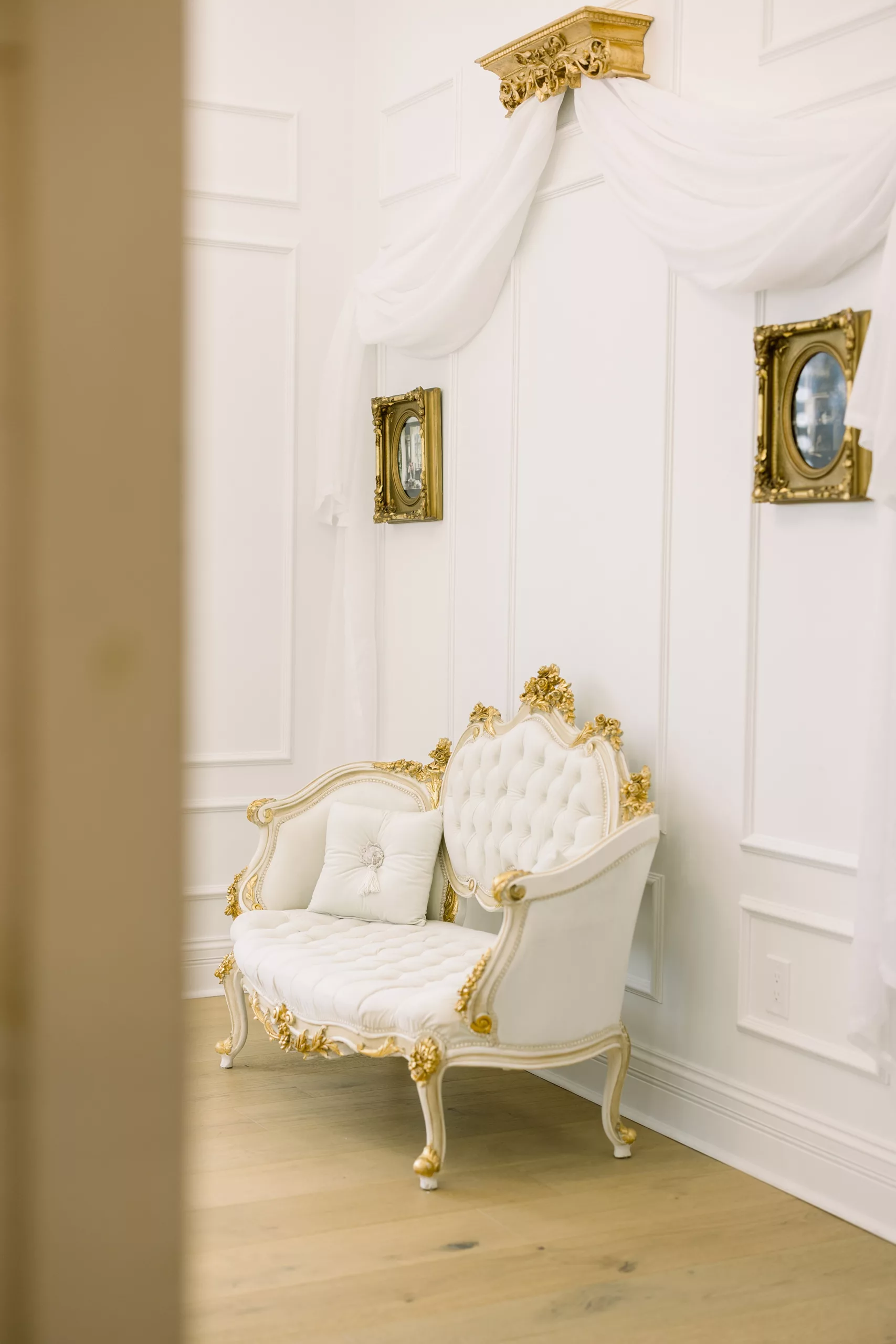 An ornate antique couch sitting under white drapes 