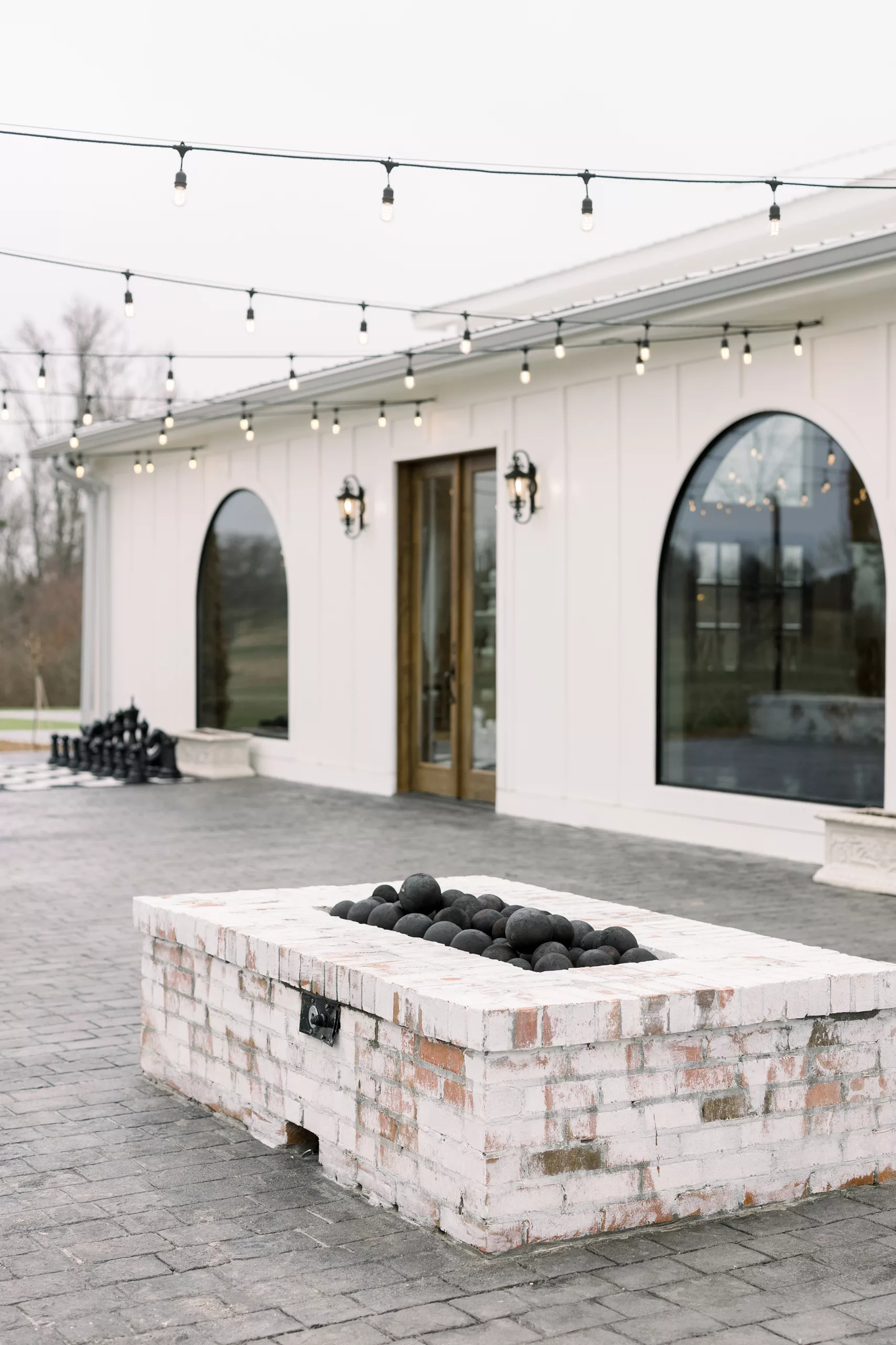 The stone patio with market lights and whitewash fire pit at blackberry ridge wedding venue