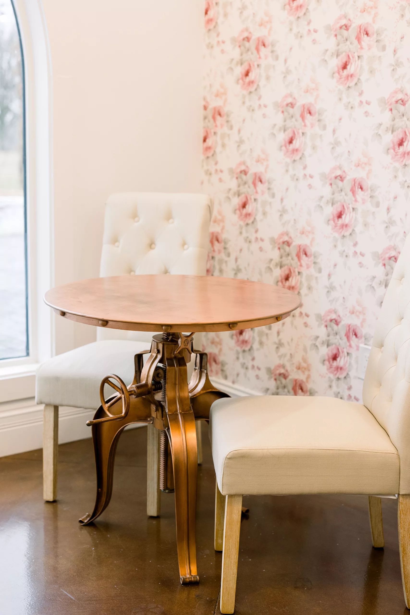 A table and chairs in the bridal suite against a pink rose wallpaper wall