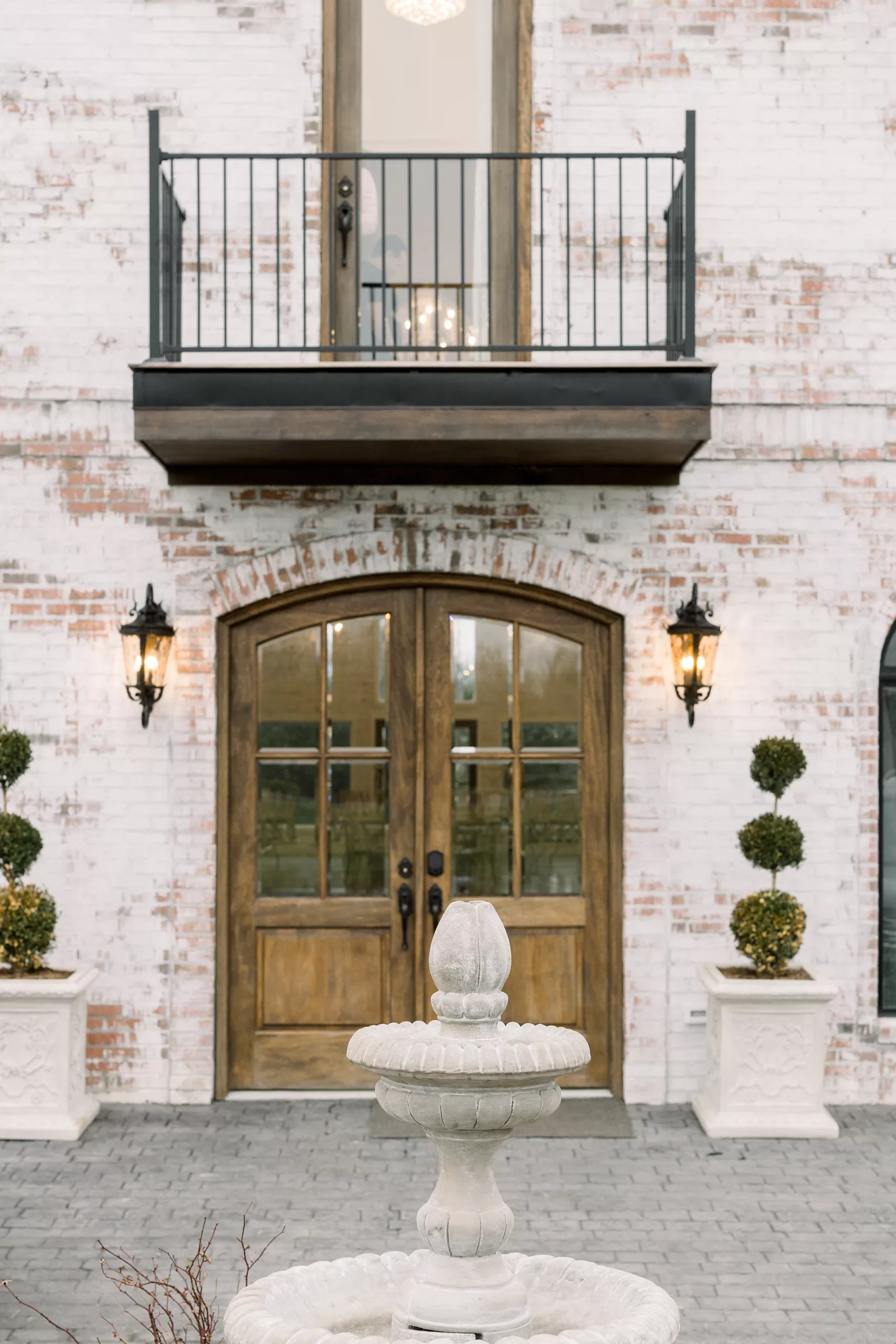 Large wooden door and fountain at the entrance of the whitewashed brick building of blackberry ridge wedding venue