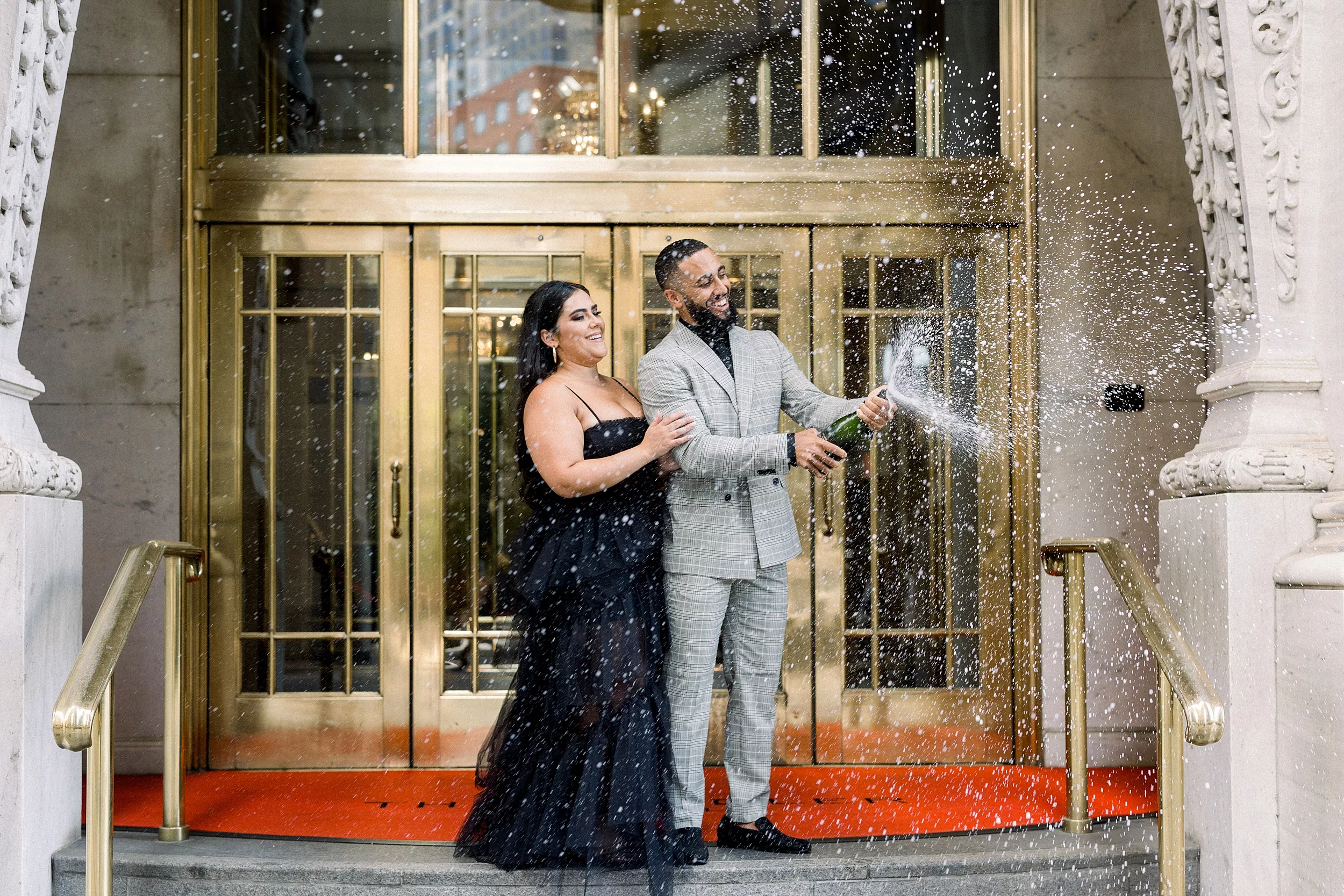NEwlyweds pop champagne at the front entrance of a Candler Hotel Atlanta wedding