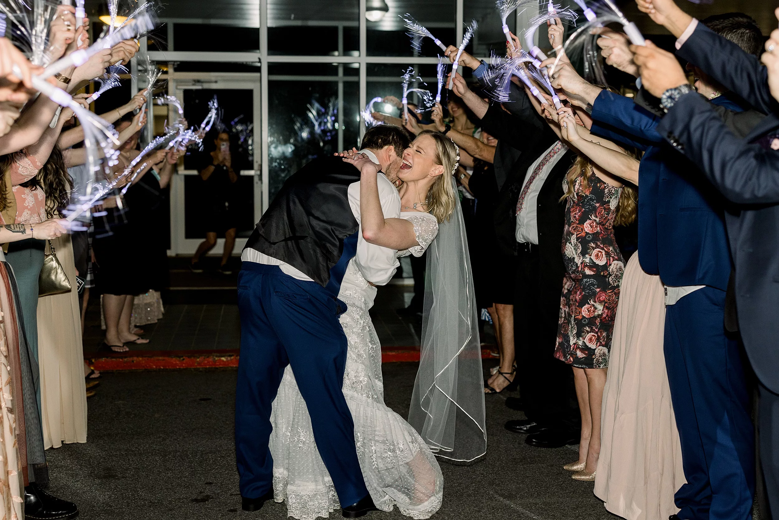 Newlyweds dip and guests wave light up sticks over them on their grand exit at a Cator Woolford Gardens Elopement