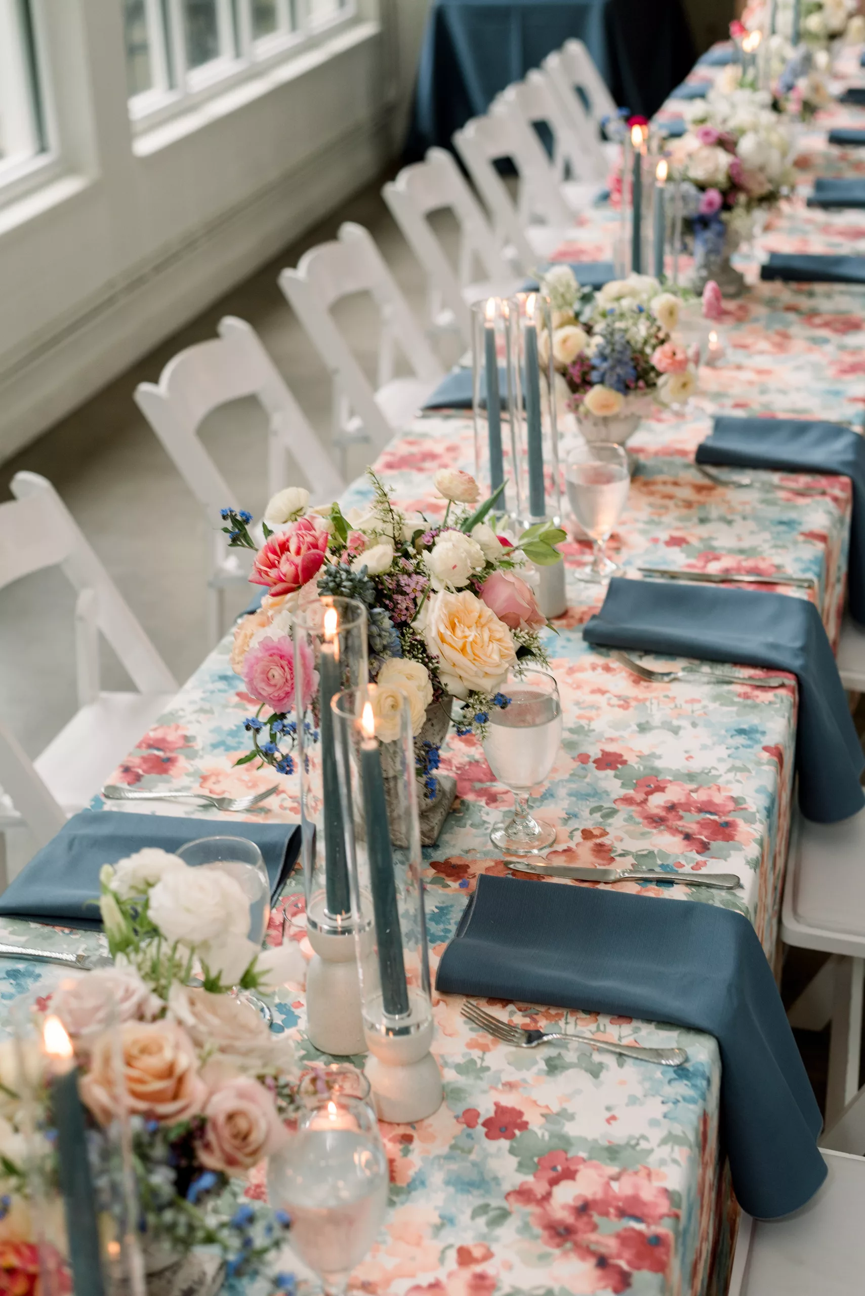Details of a long table setting with floral print linen and blue candles Cator Woolford Gardens Elopement