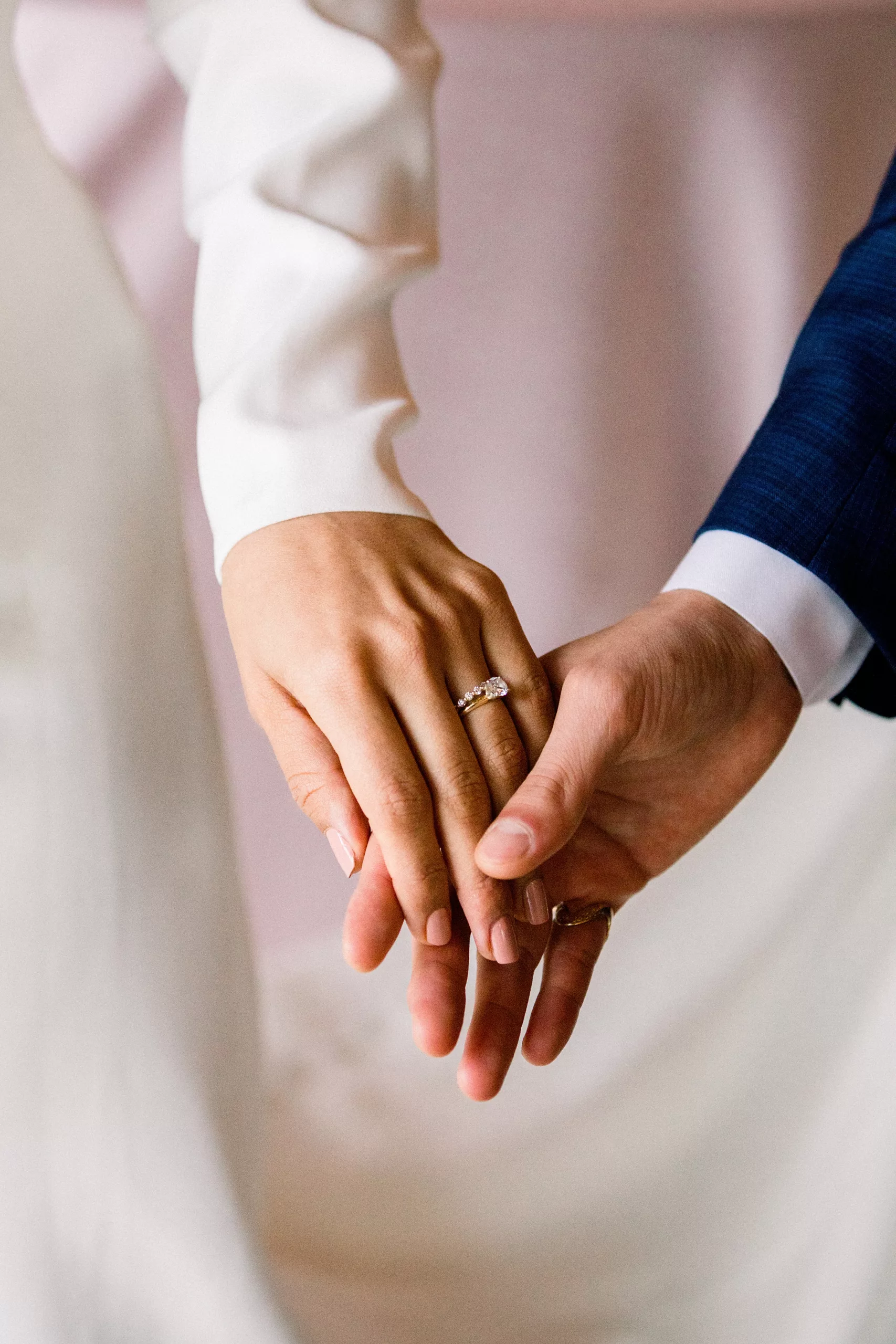 Details of newlyweds holding hands with the bride's rings