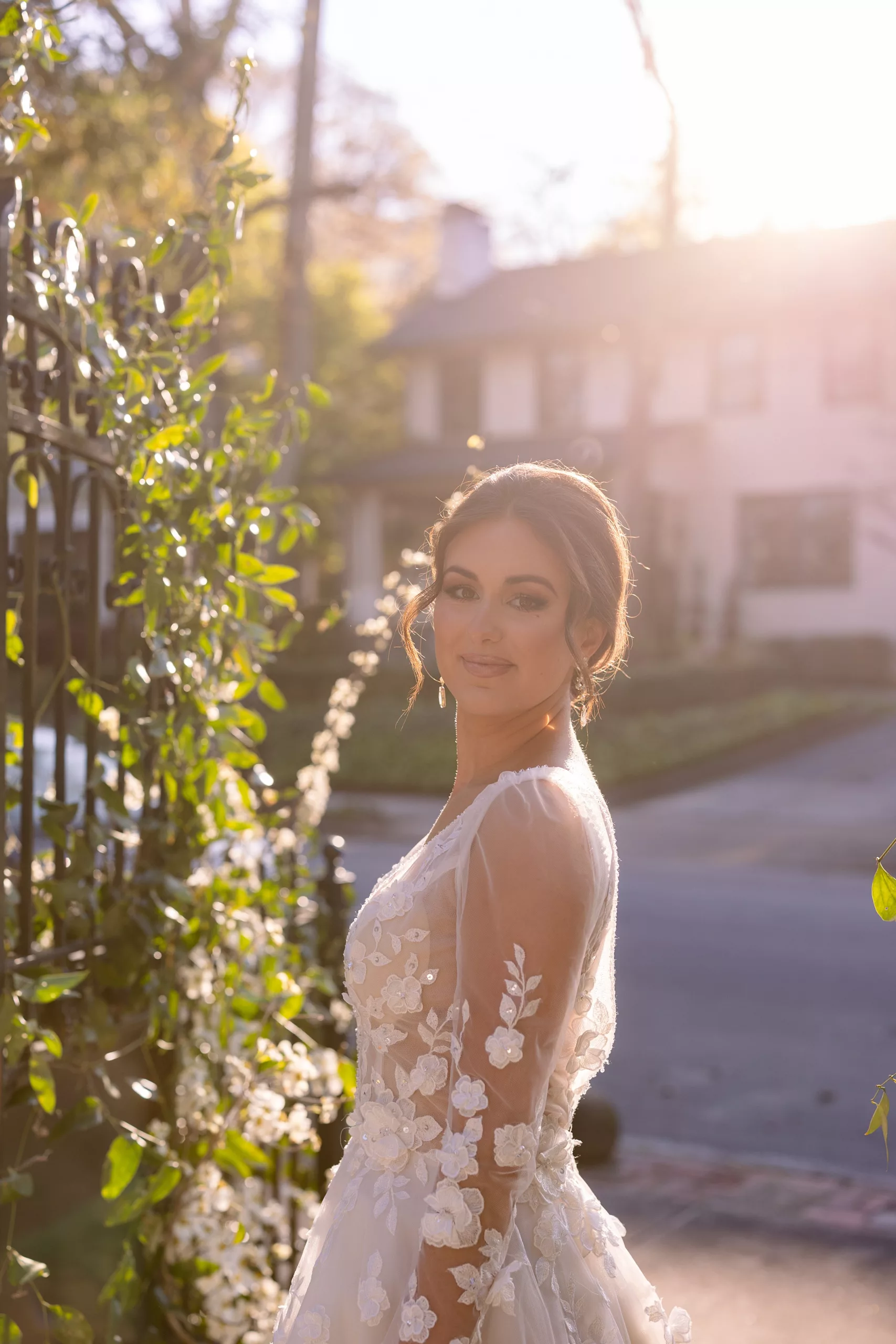 A bride stands at an iron gate covered in vines at sunset Wedding Photography Timeline