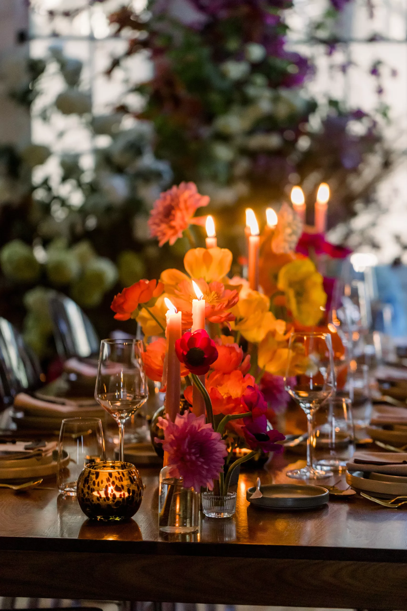 Details of a wedding ceremony table setting with lit candles and colorful flowers