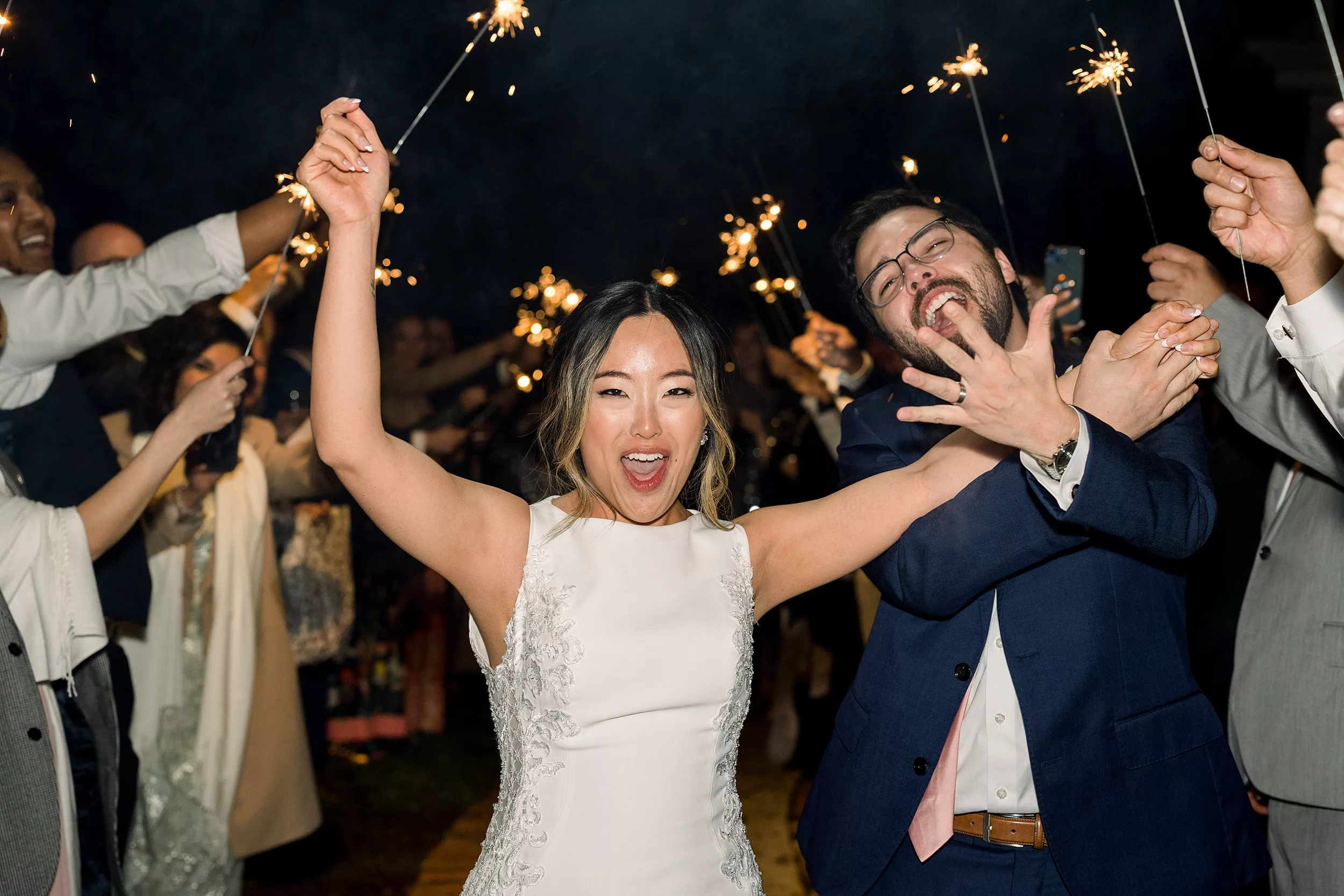 Newlyweds celebrate surrounded by sparklers while exiting their wedding
