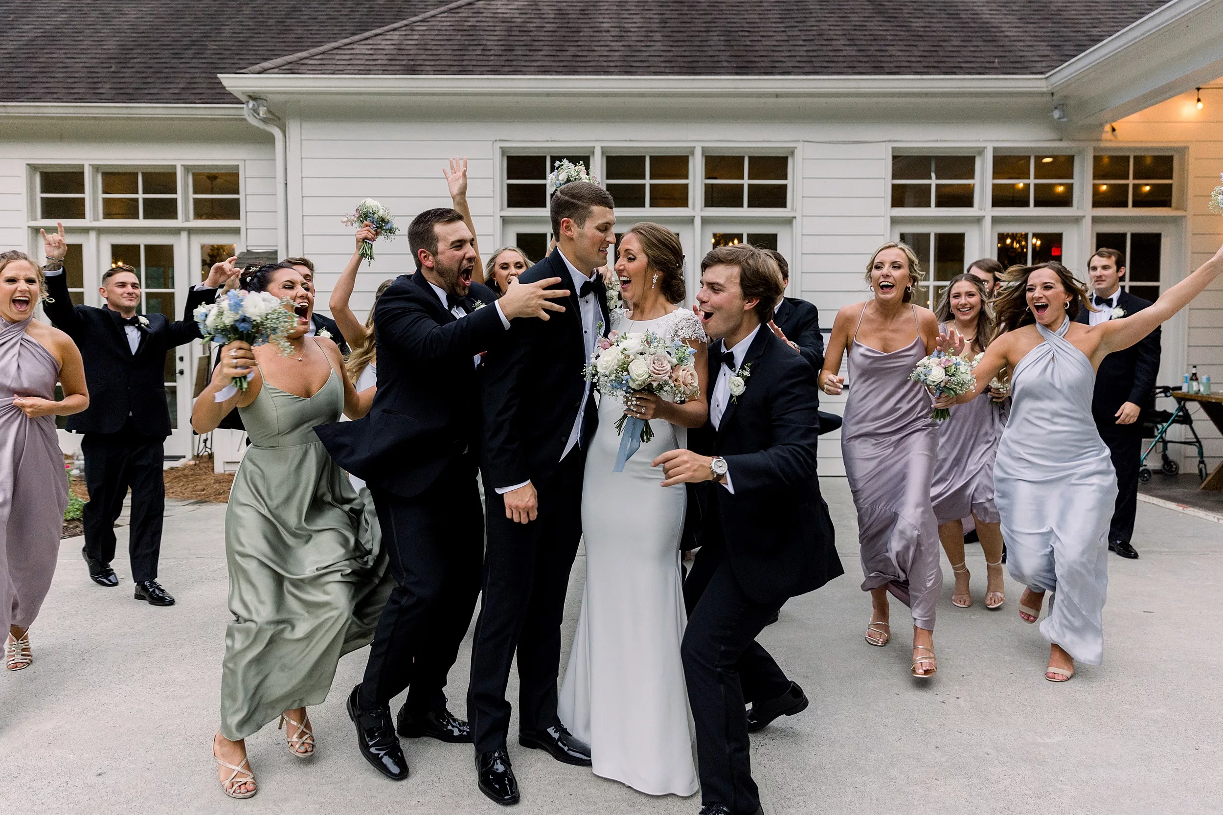 Newlyweds celebrate surrounded by their wedding party on a patio wedding planner vs coordinator