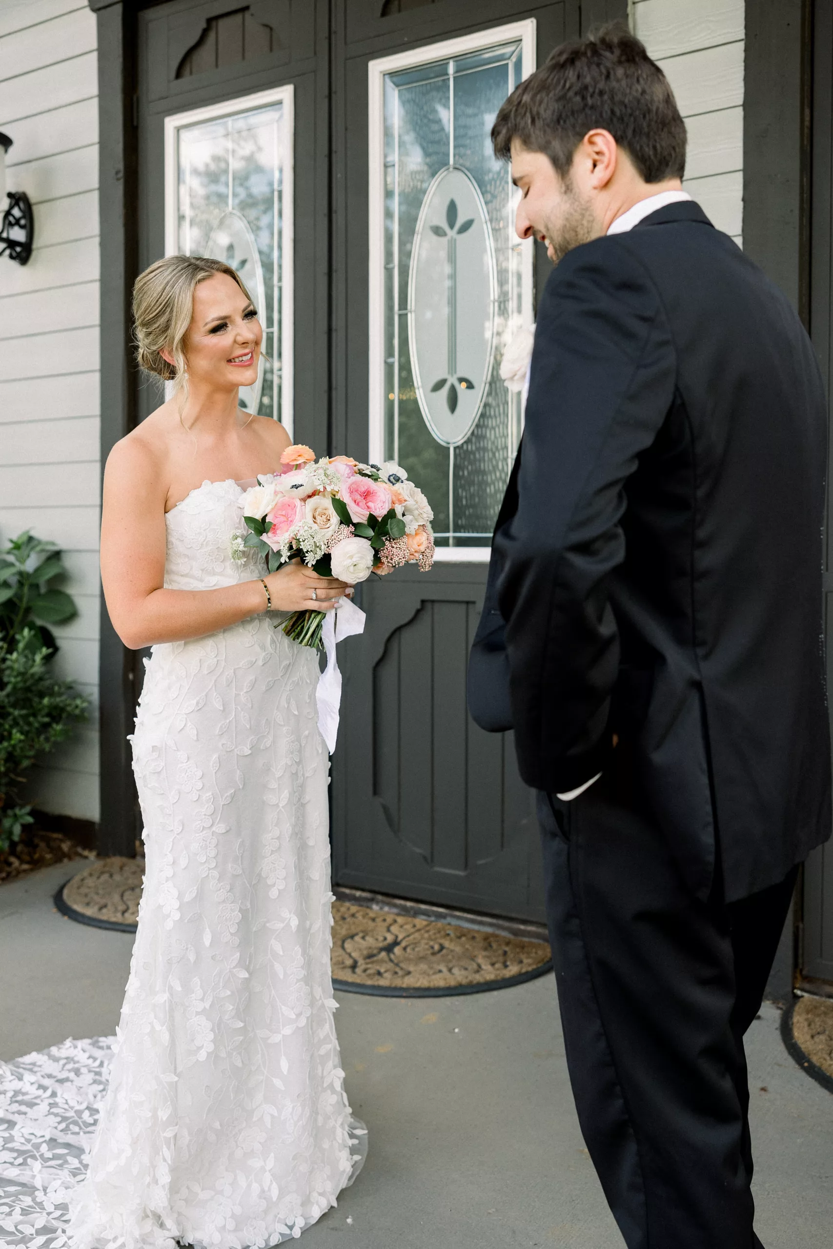 A groom stands with hands in his pockets while crying after seeing his bride for the first time on their wedding day before the ceremony on a porch