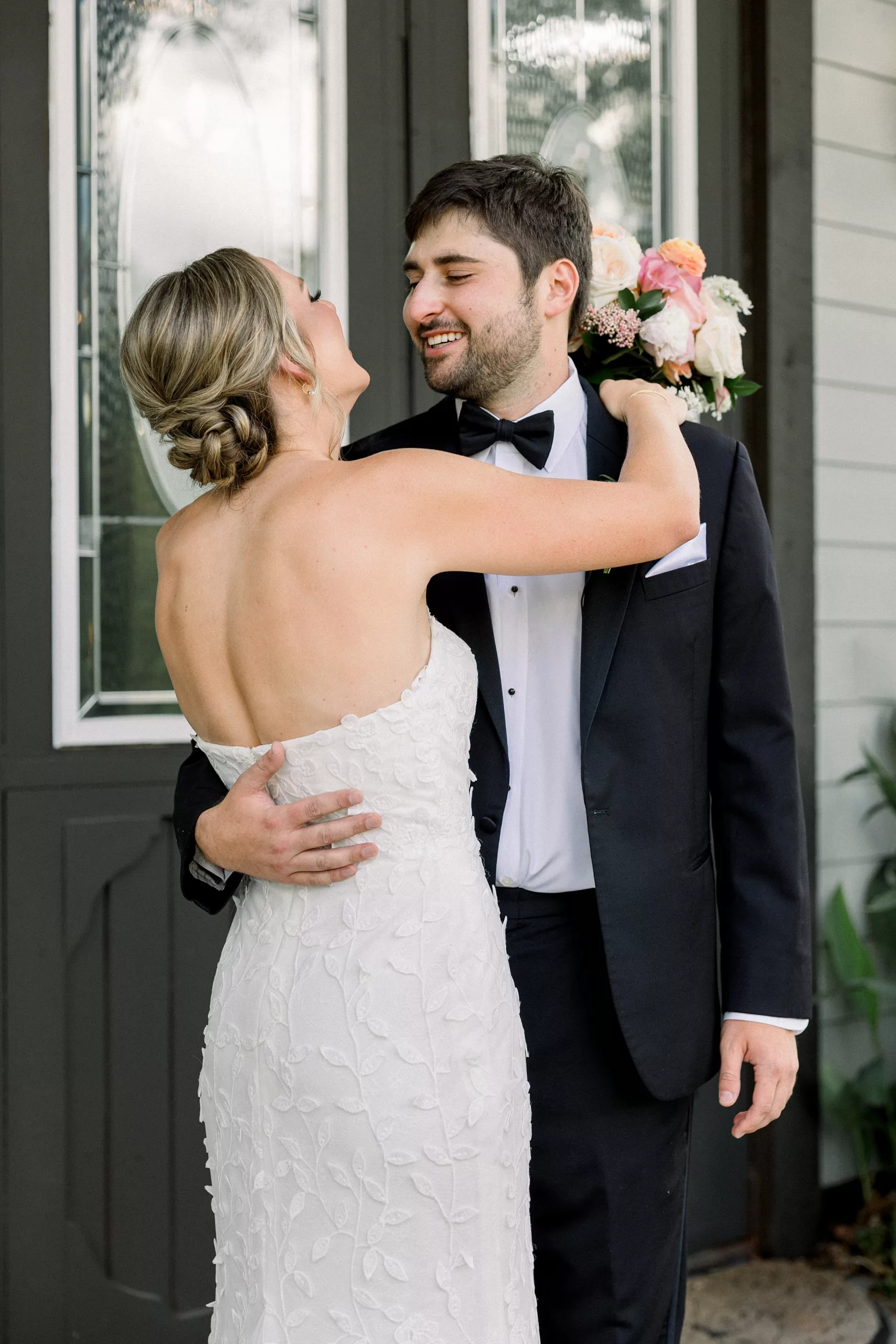 A groom smiles big as he hugs his bride after seeing her for the first time in her dress