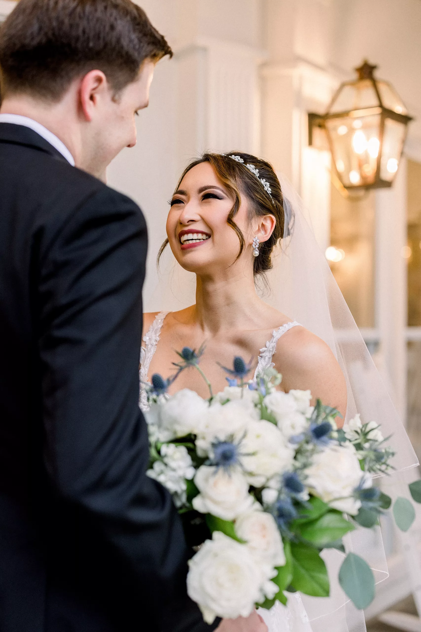 A bride in a lace dress smiles at her husband as he sees her for the first time at their first look wedding