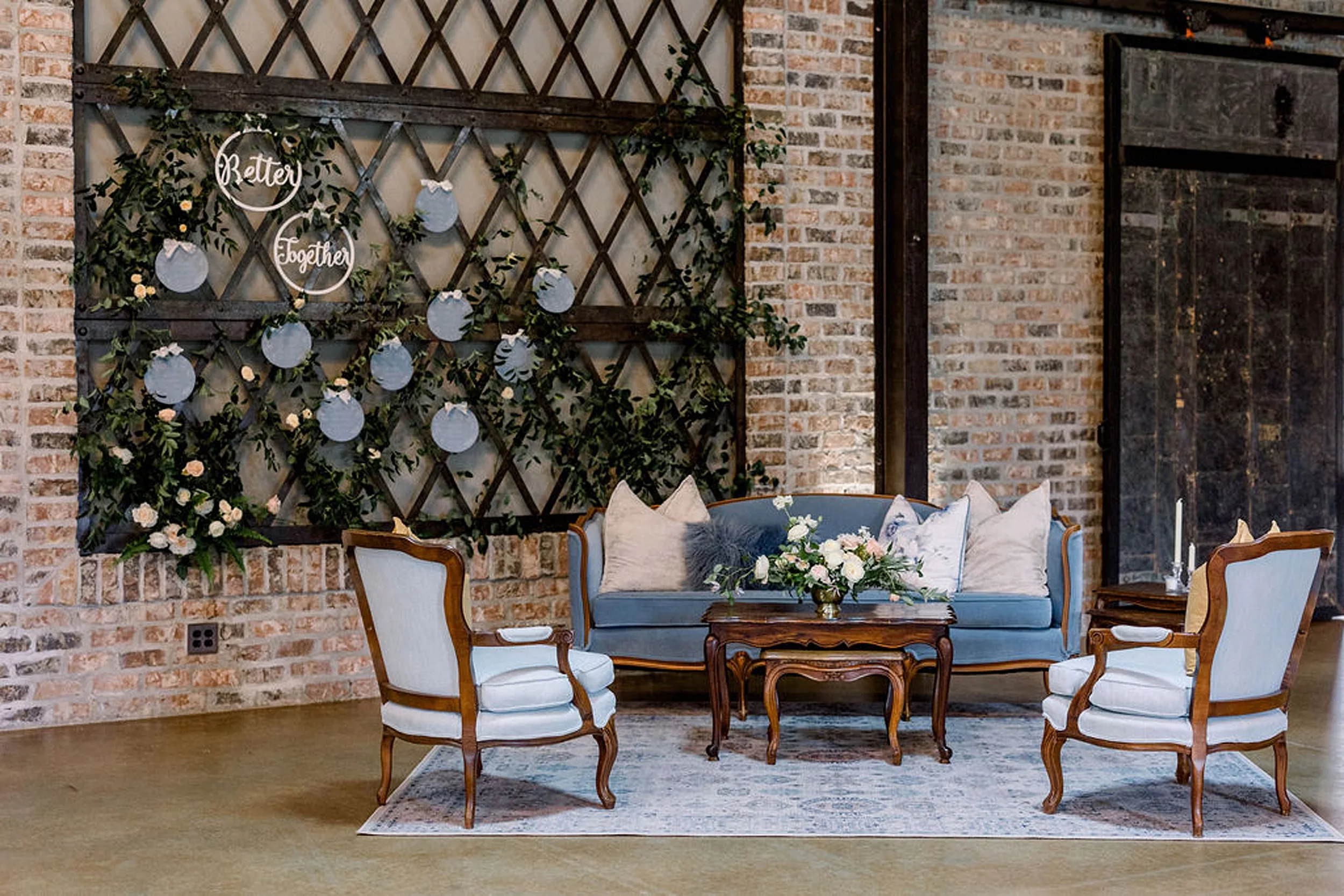 Details of a blue couch and chairs set in a lobby by a wooden decorated wall for a wedding