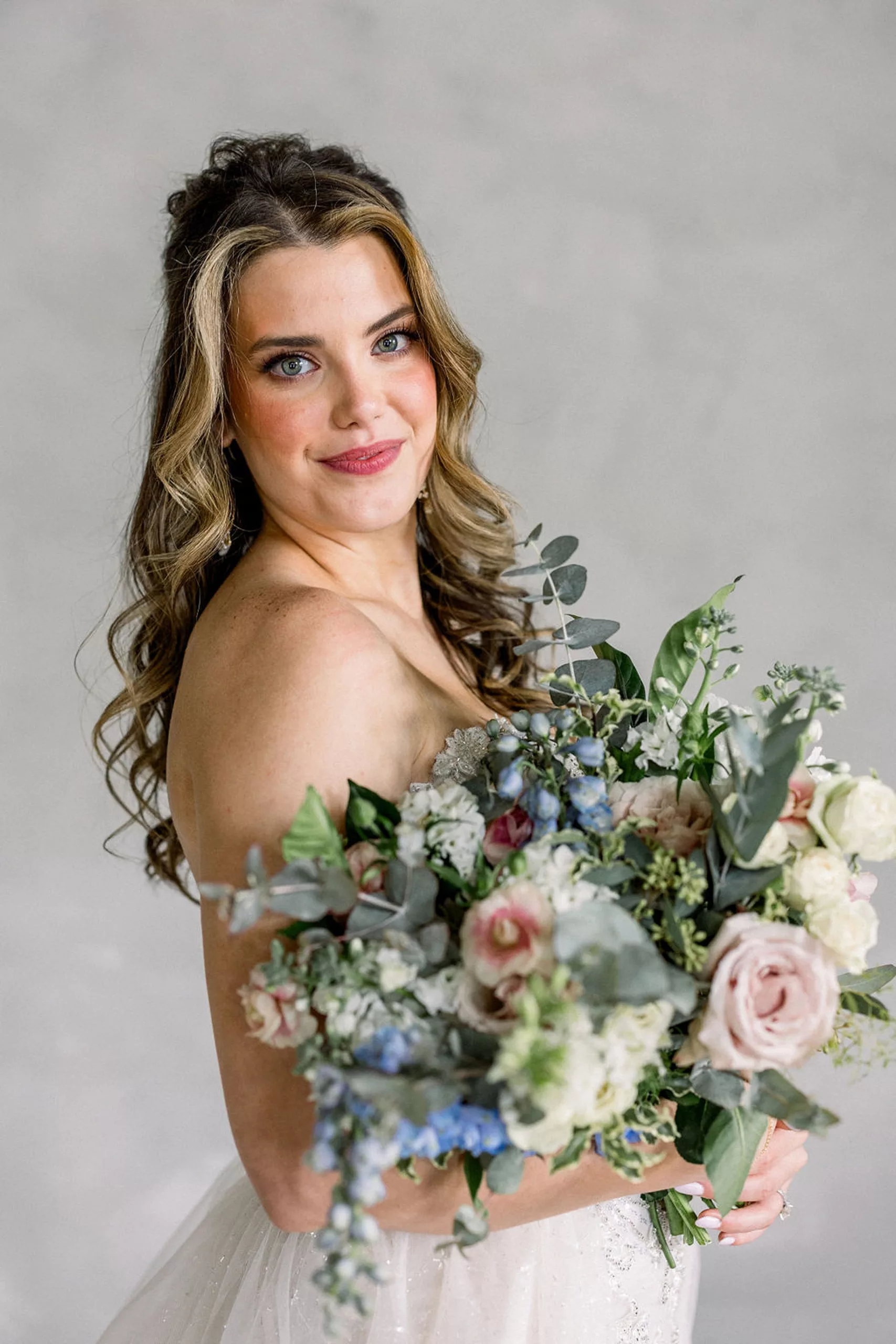 A bride stands holding her large bouquet