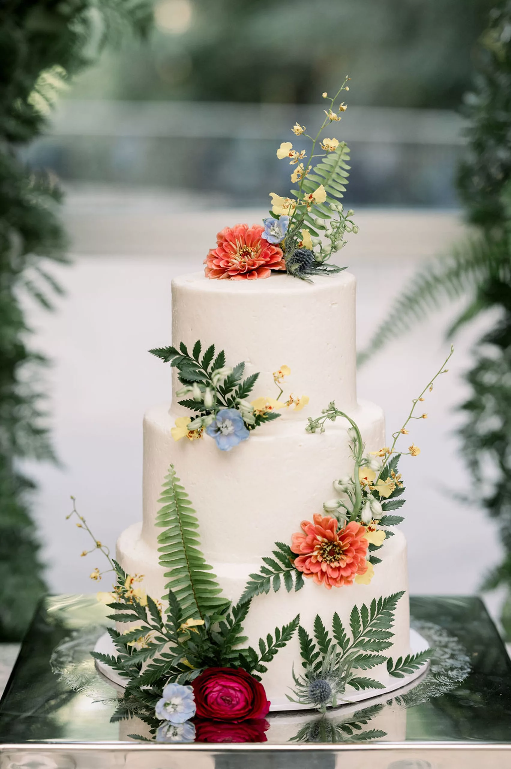 Details of a dinosaur theme cake with ferns and colorful flowers