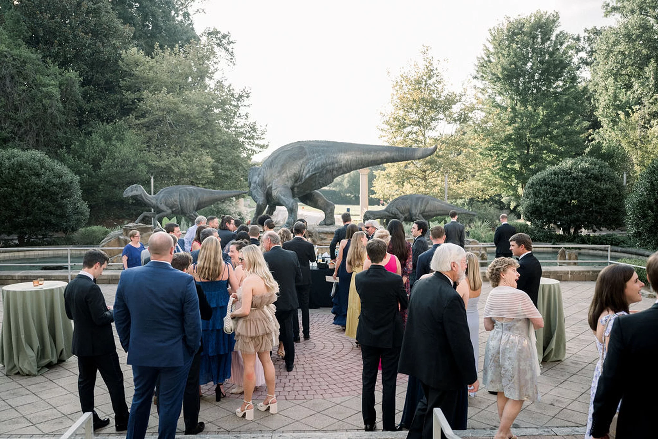A wide view of a wedding reception set up in a garden surrounded by dinosaur statues