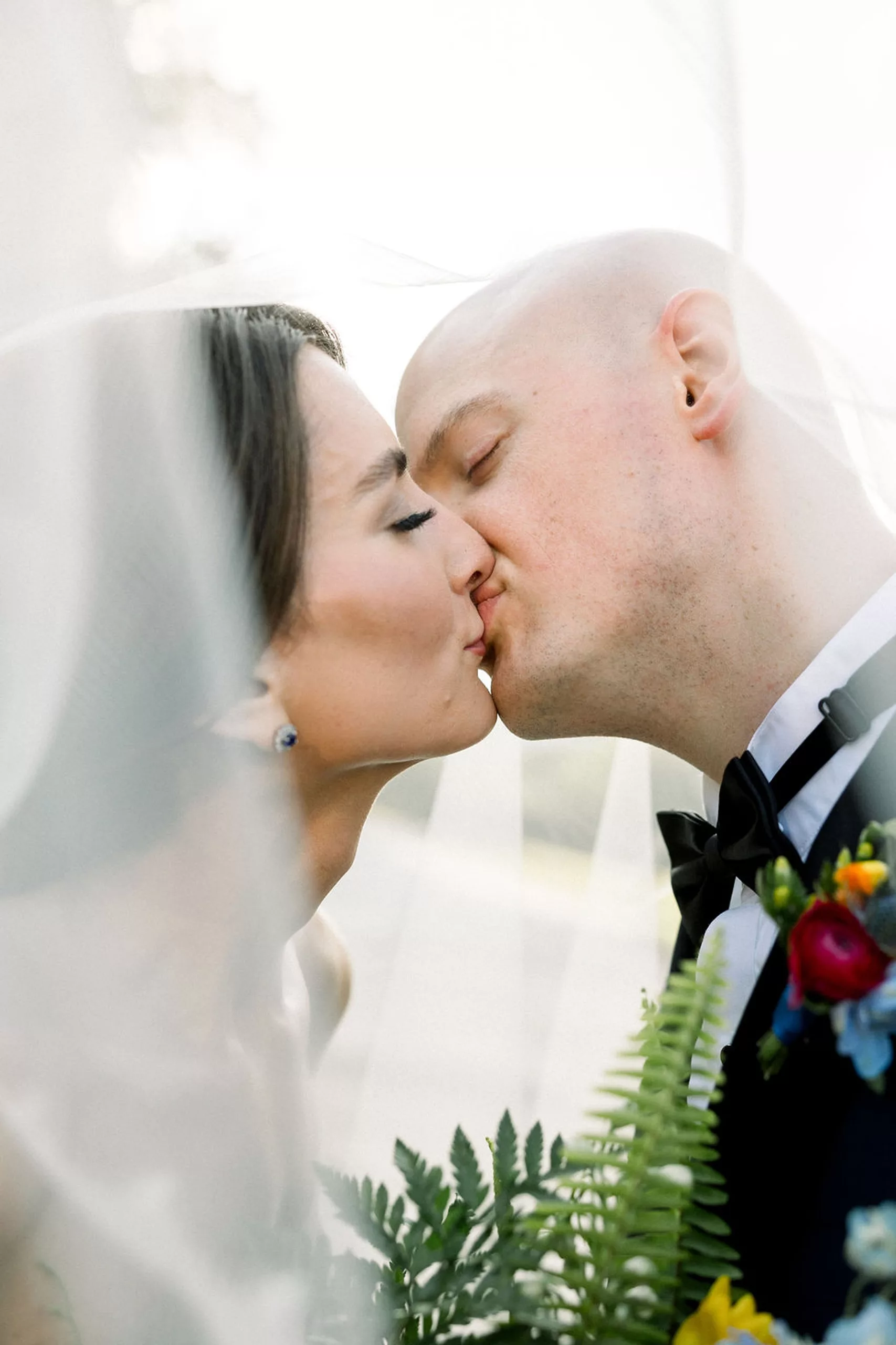 Newlyweds kiss while under the veil outside at their jurassic park wedding
