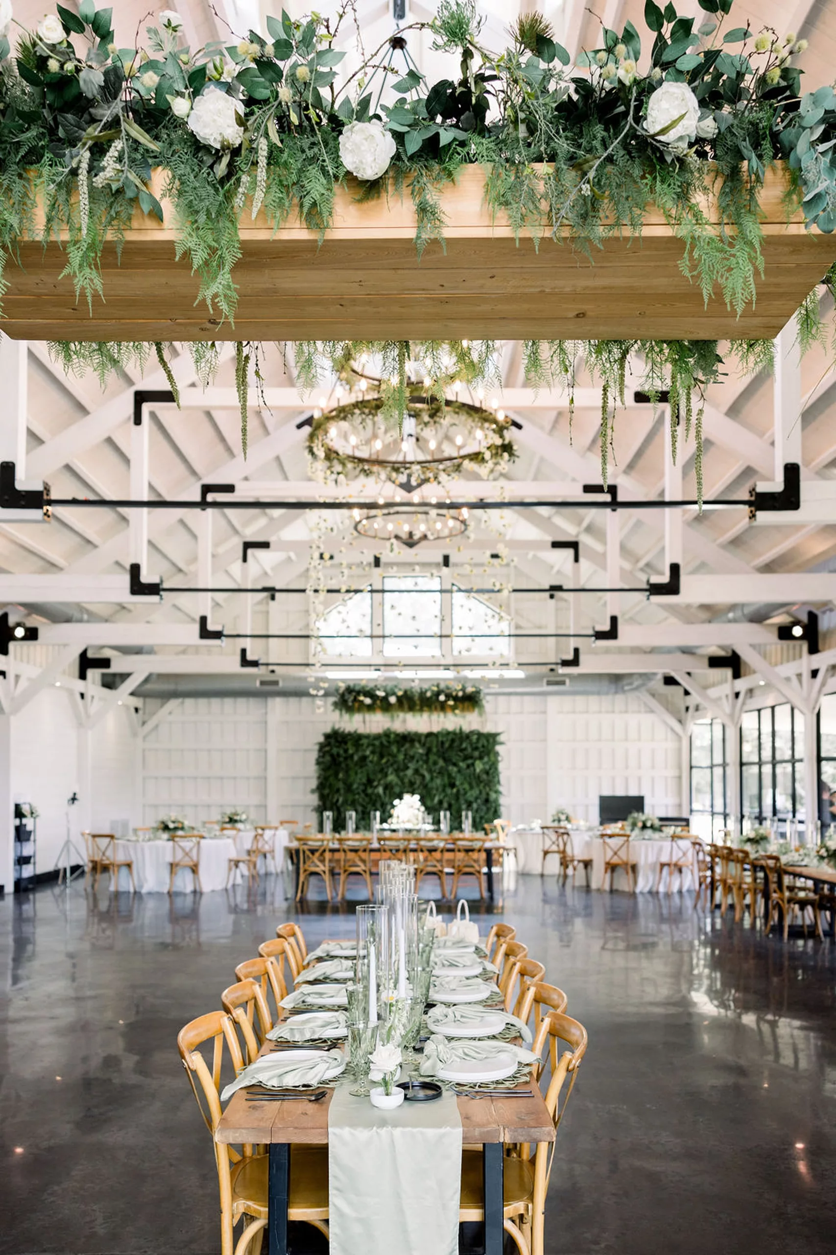 Details of a wedding venue set up with long tables and wooden chairs and white florals