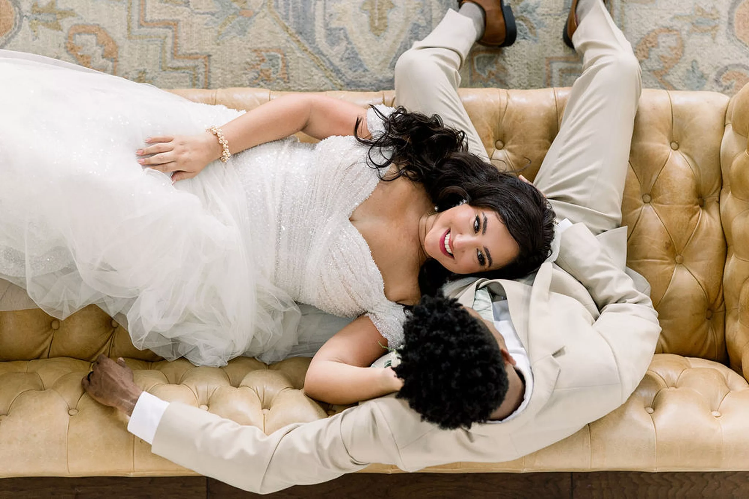 A bride lays in the lap of her groom on a tan leather couch in the meadows at mossy creek wedding venue