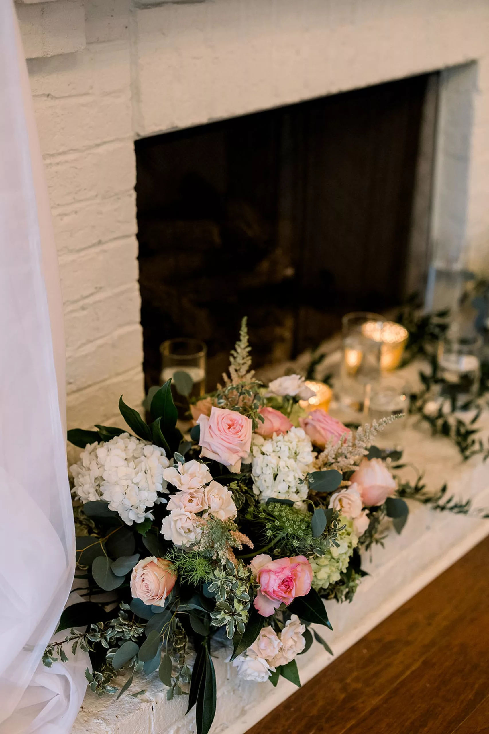 Details of pink and white flowers decorating a white fireplace at the payne-corley house wedding venue