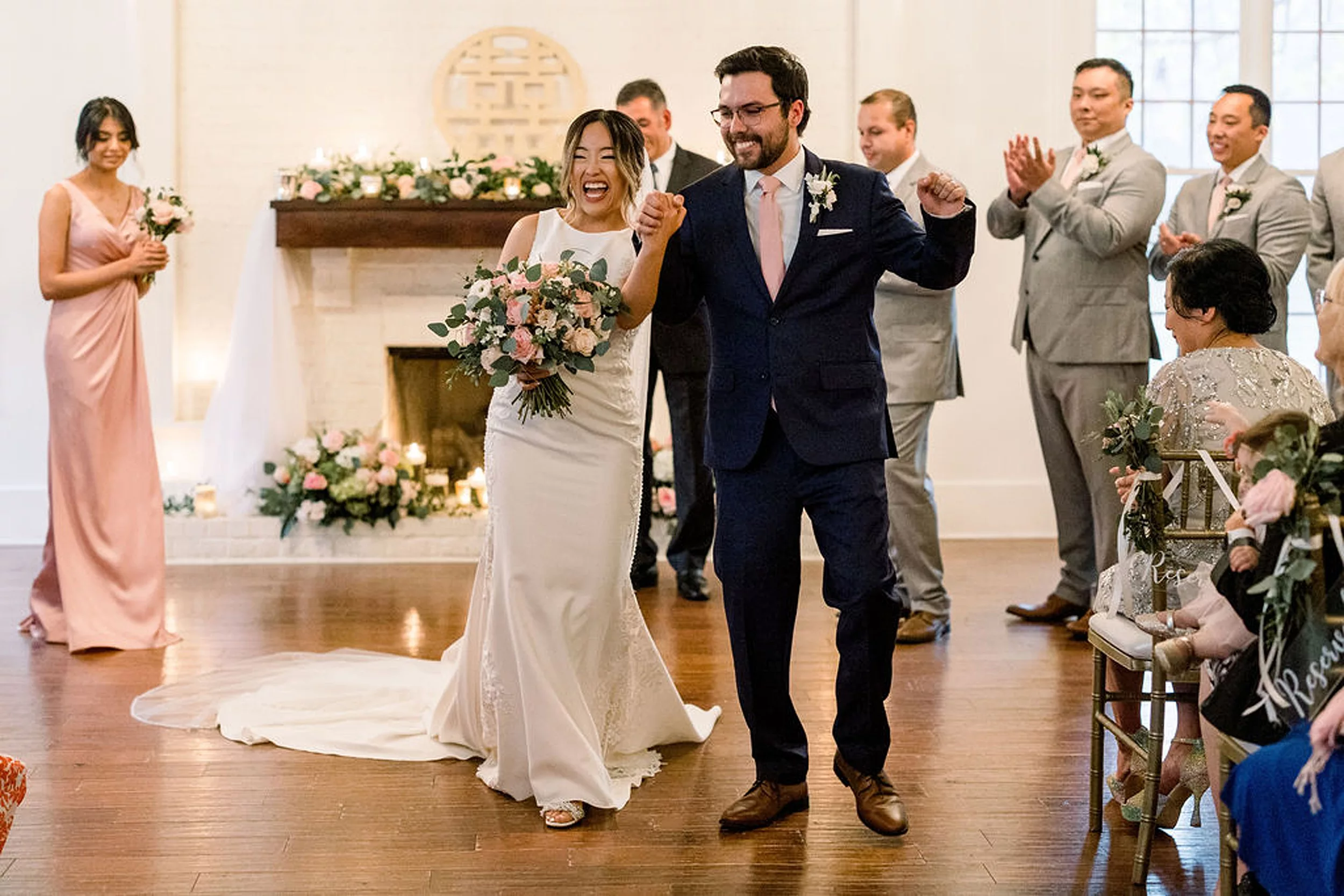 Newlyweds celebrate and raise their hands as they walk up the aisle of their payne-corley house wedding ceremony