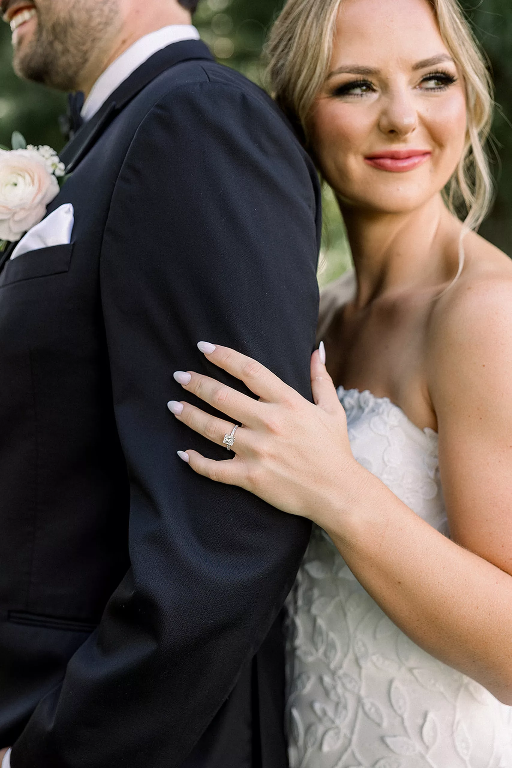 Details of a bride holding her groom's arm with her ring hand