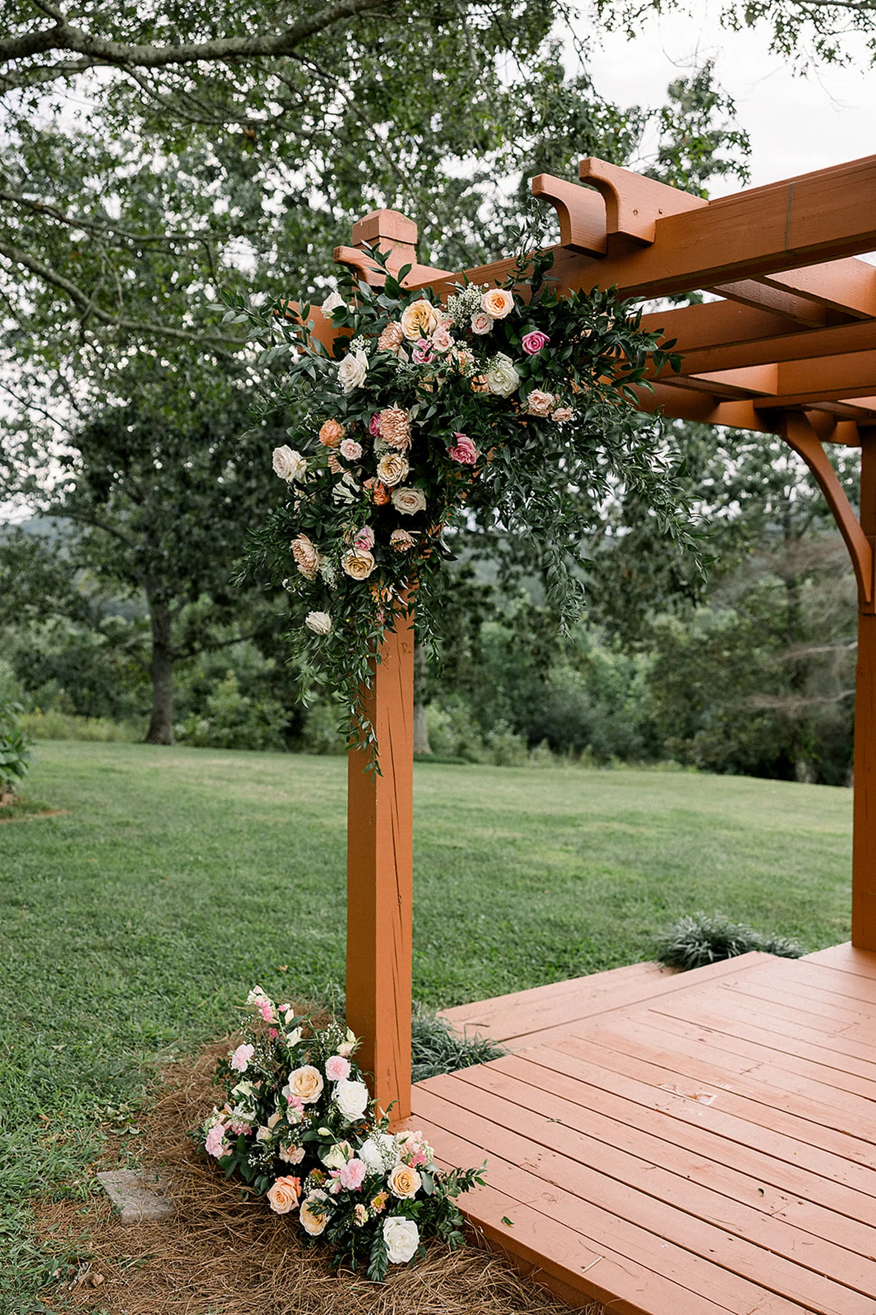 Details of pink and white florals decorating a brown wood pergola for a White Oaks Vineyard wedding ceremony