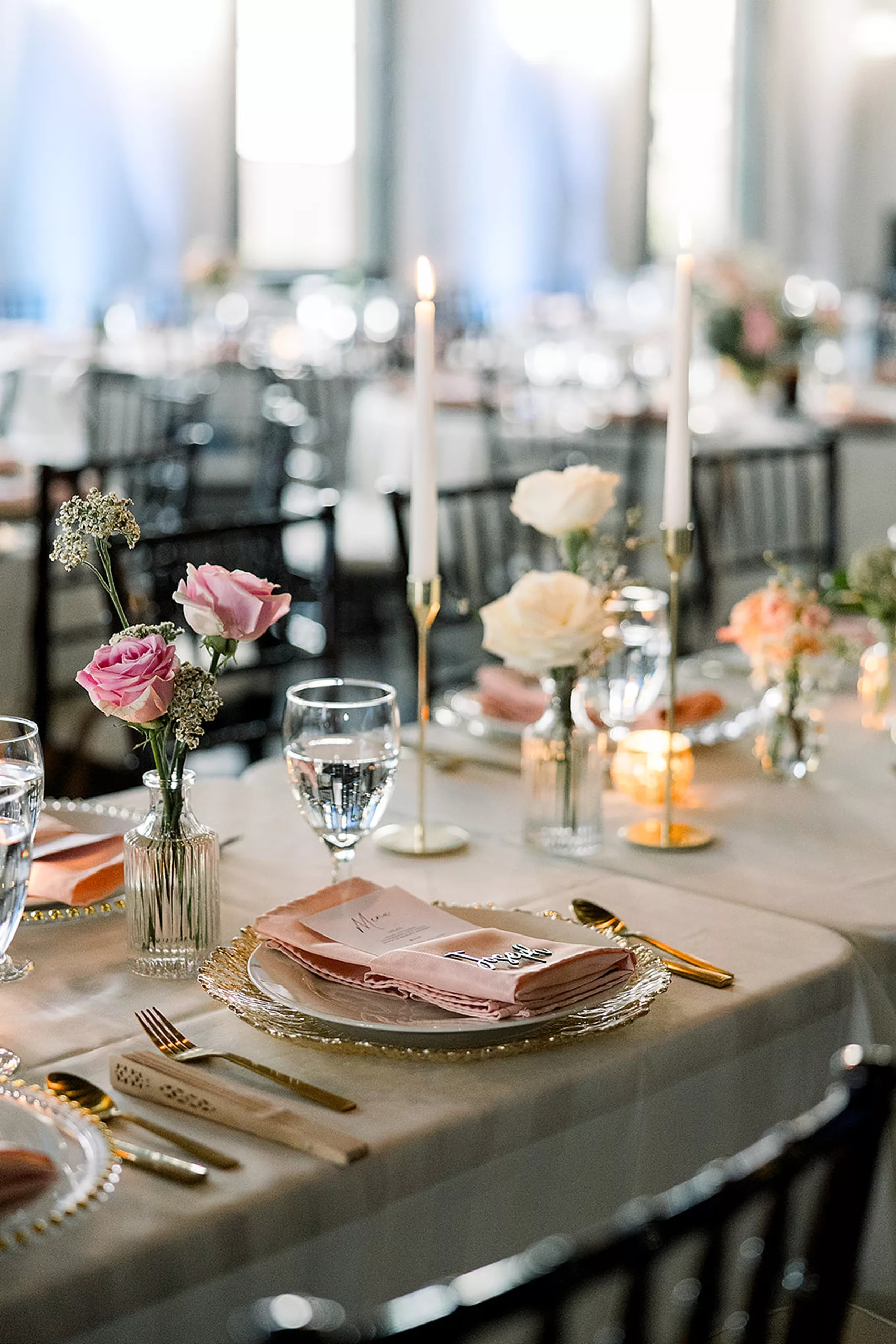 Details of a wedding reception table set up with pink linens and roses and gold silverware at the White Oaks Vineyard wedding venue