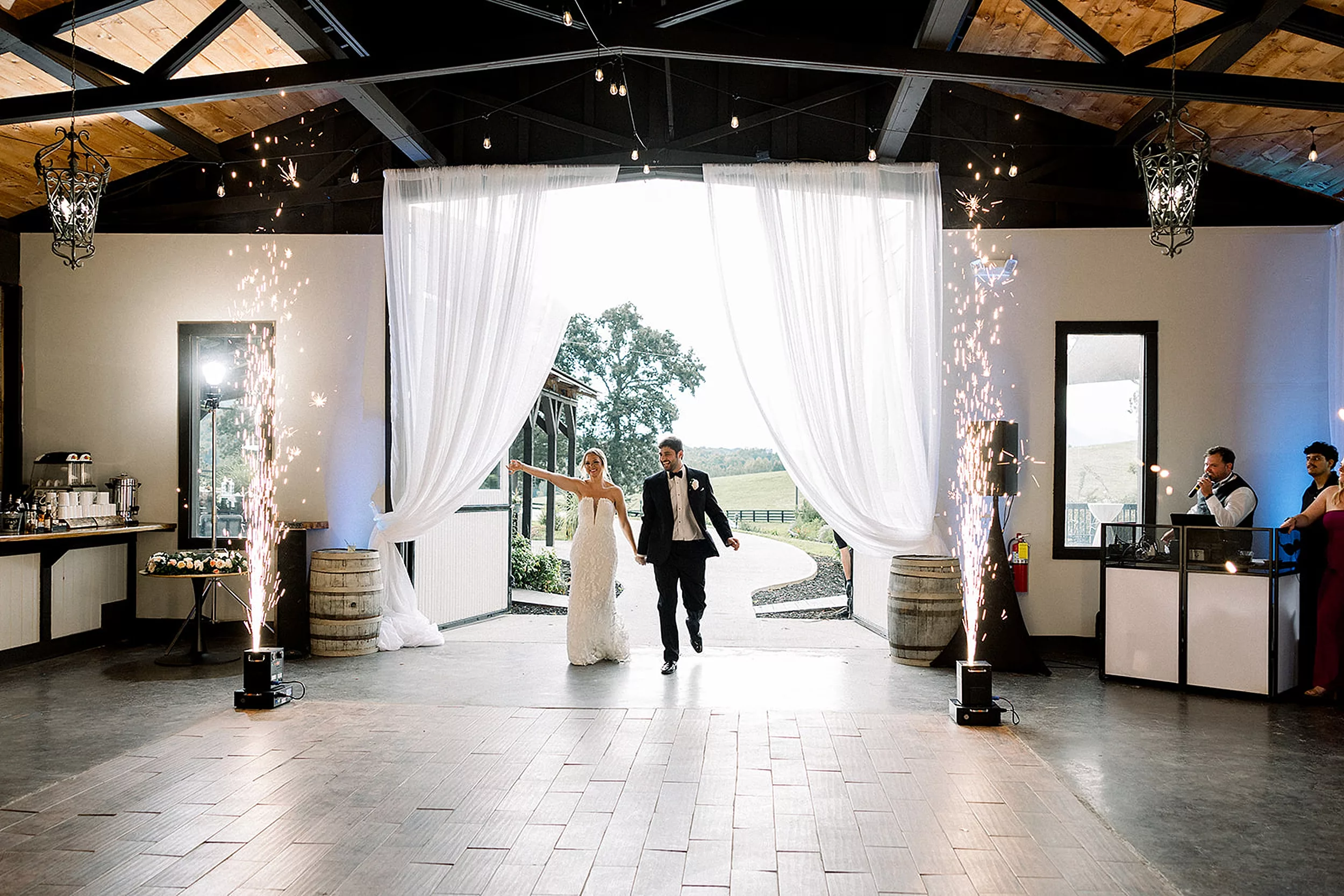Newlyweds enter their White Oaks Vineyard wedding reception through large drapes and sparkler machines