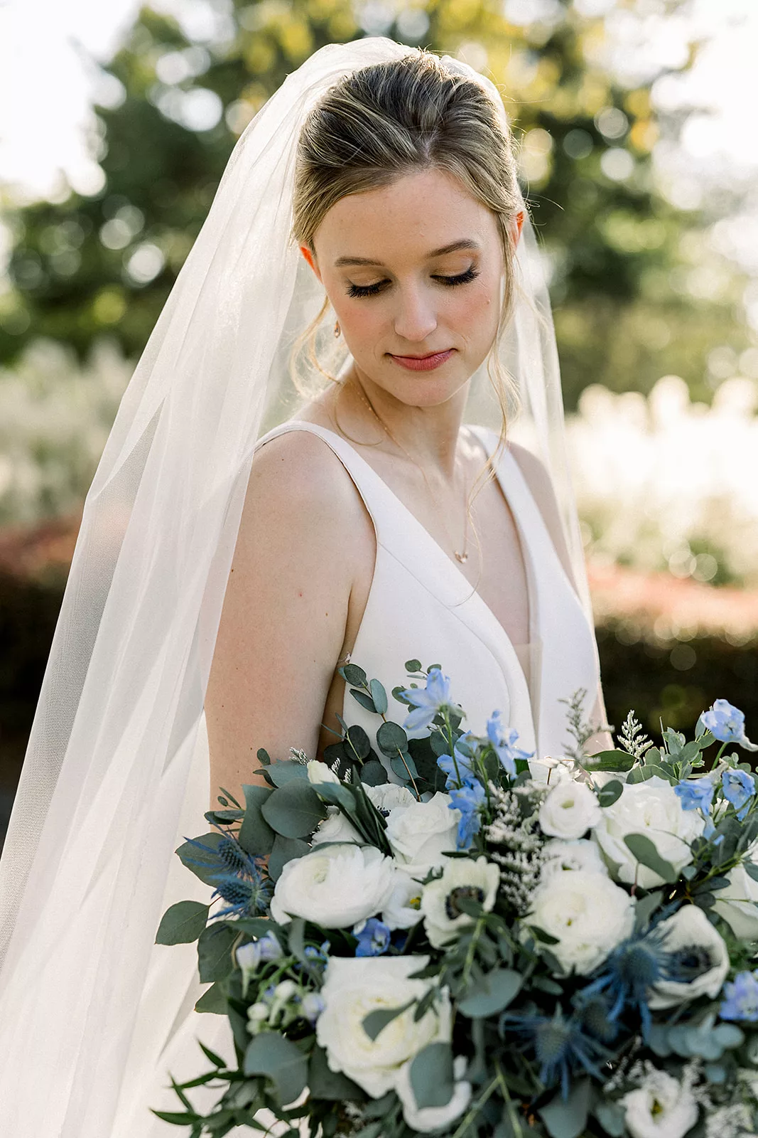 A bride looks down at her blue and white florals in her hand at a Curahee Club Wedding