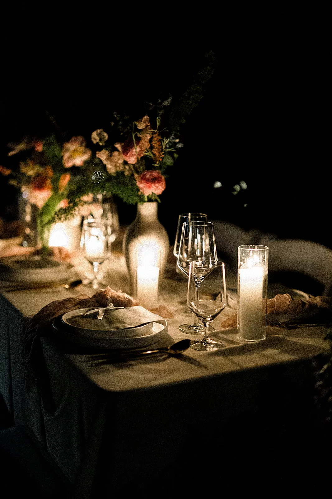 Details of a wedding reception table set up at night with candles