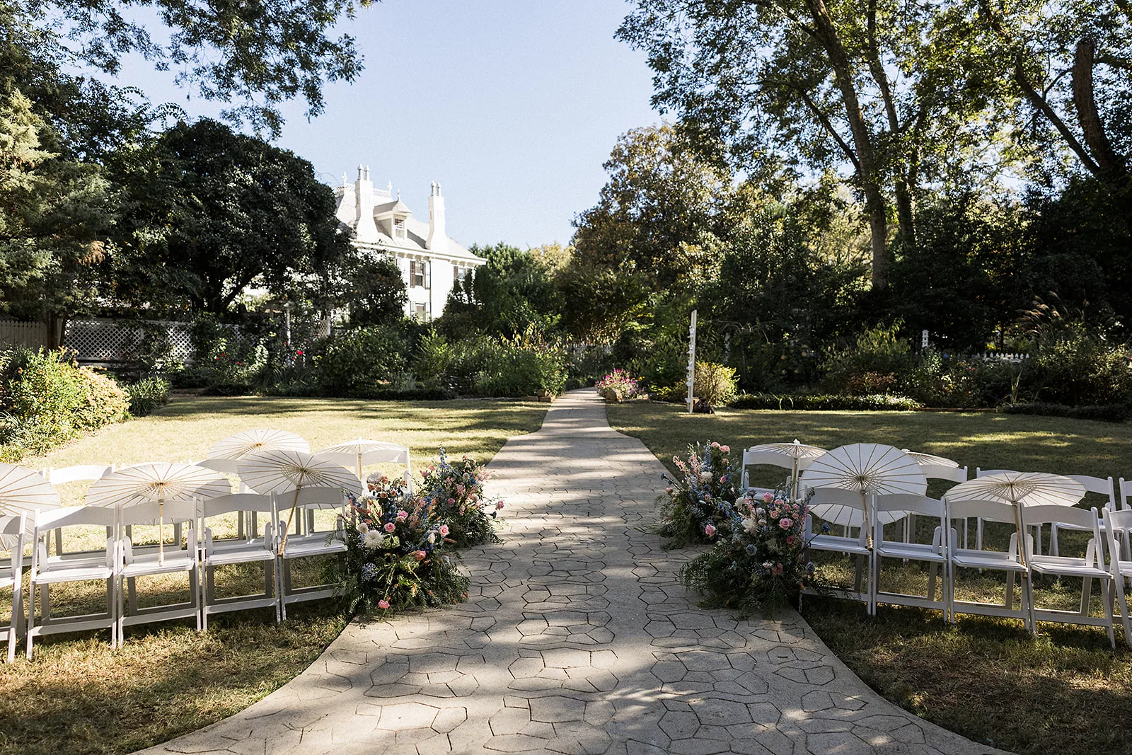 A view in the garden lawn of a wedding ceremony with a stone path