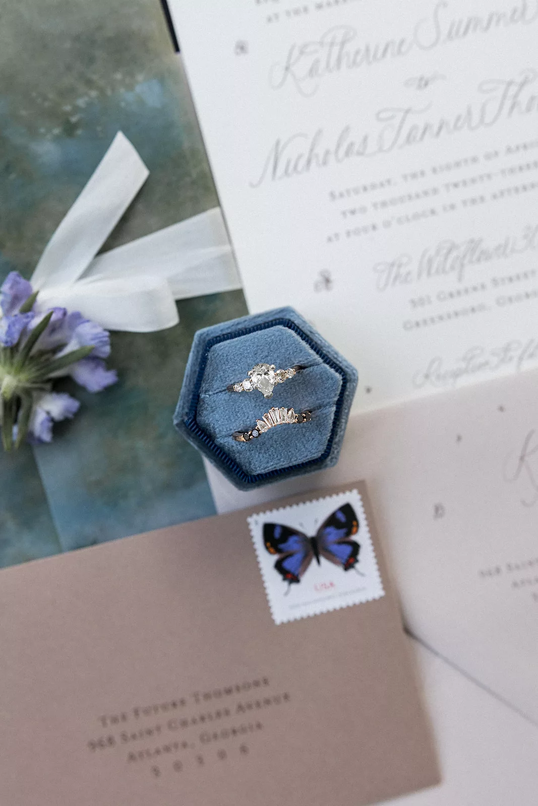 Details of wedding bands in a ring box surrounded by wedding invitations on a table
