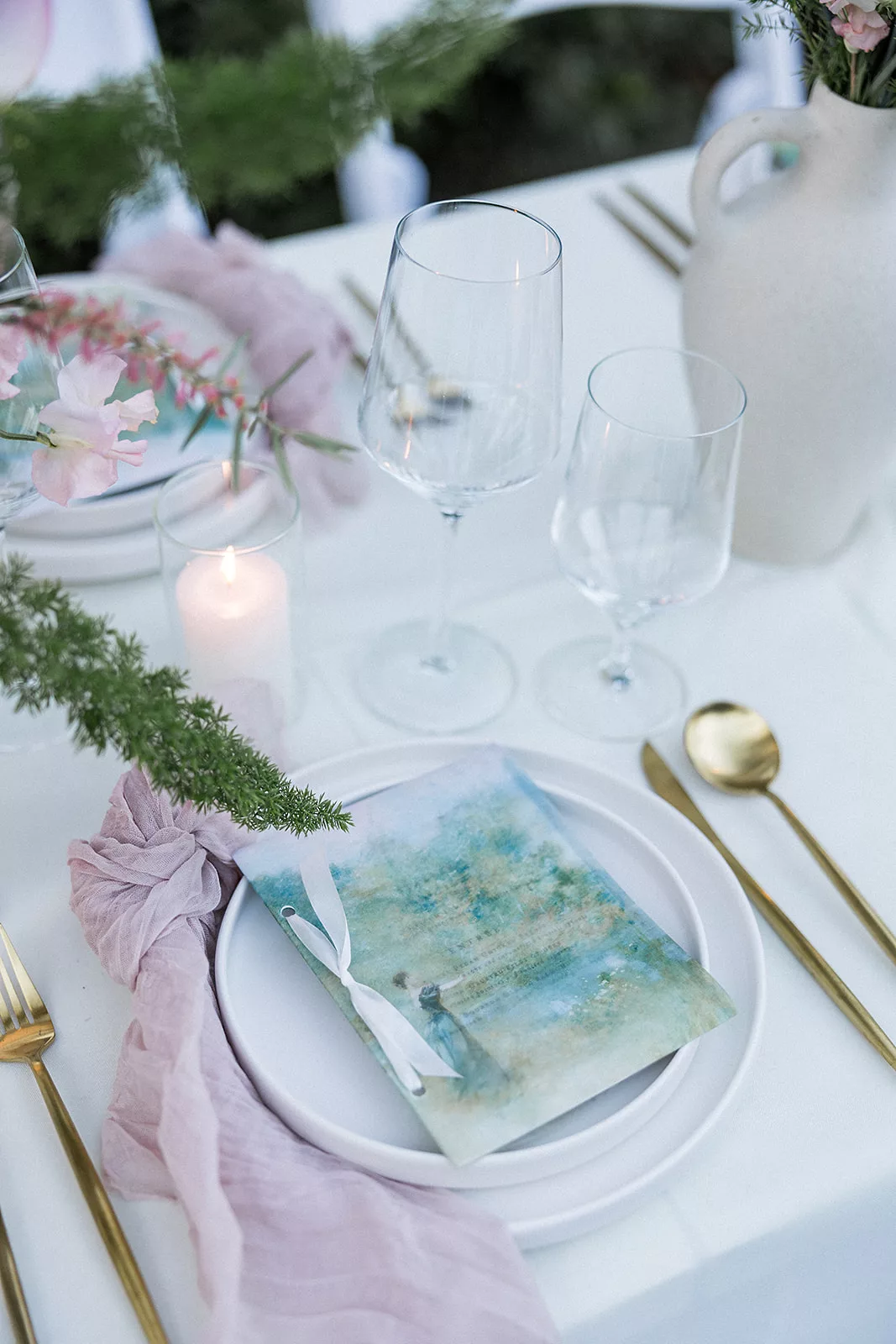 Details of an outdoor wedding reception table setting with pink linen and gold silverware