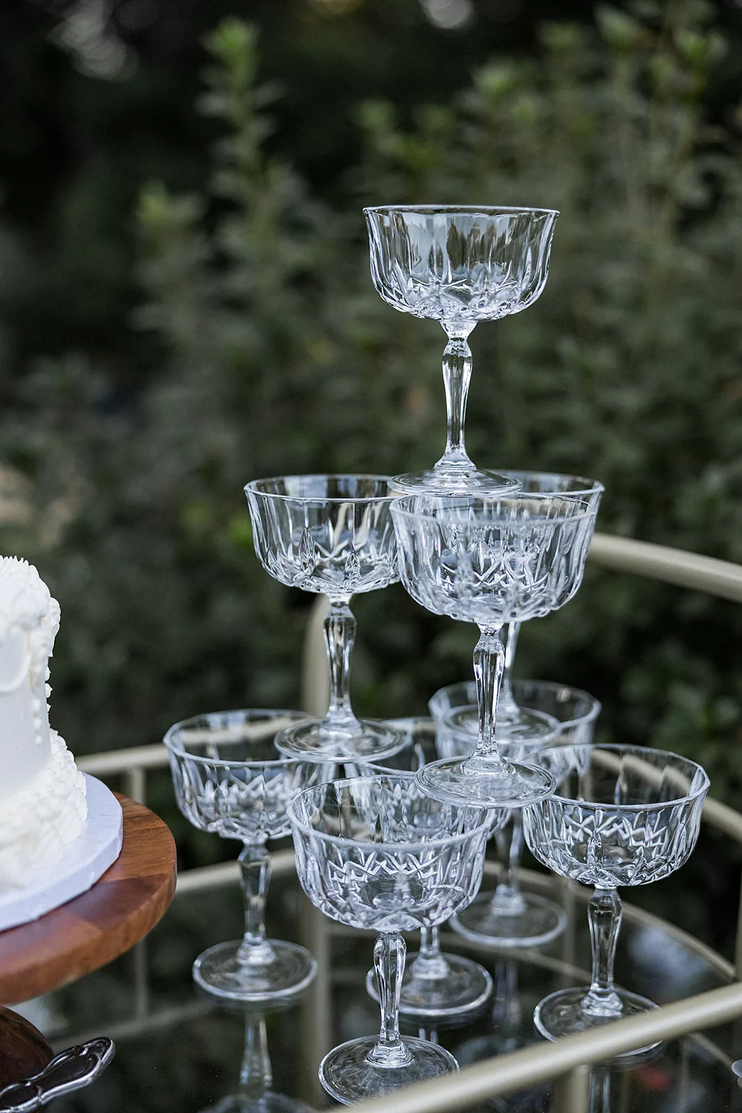 Details of a stack of crystal glasses on a cake cart in a garden
